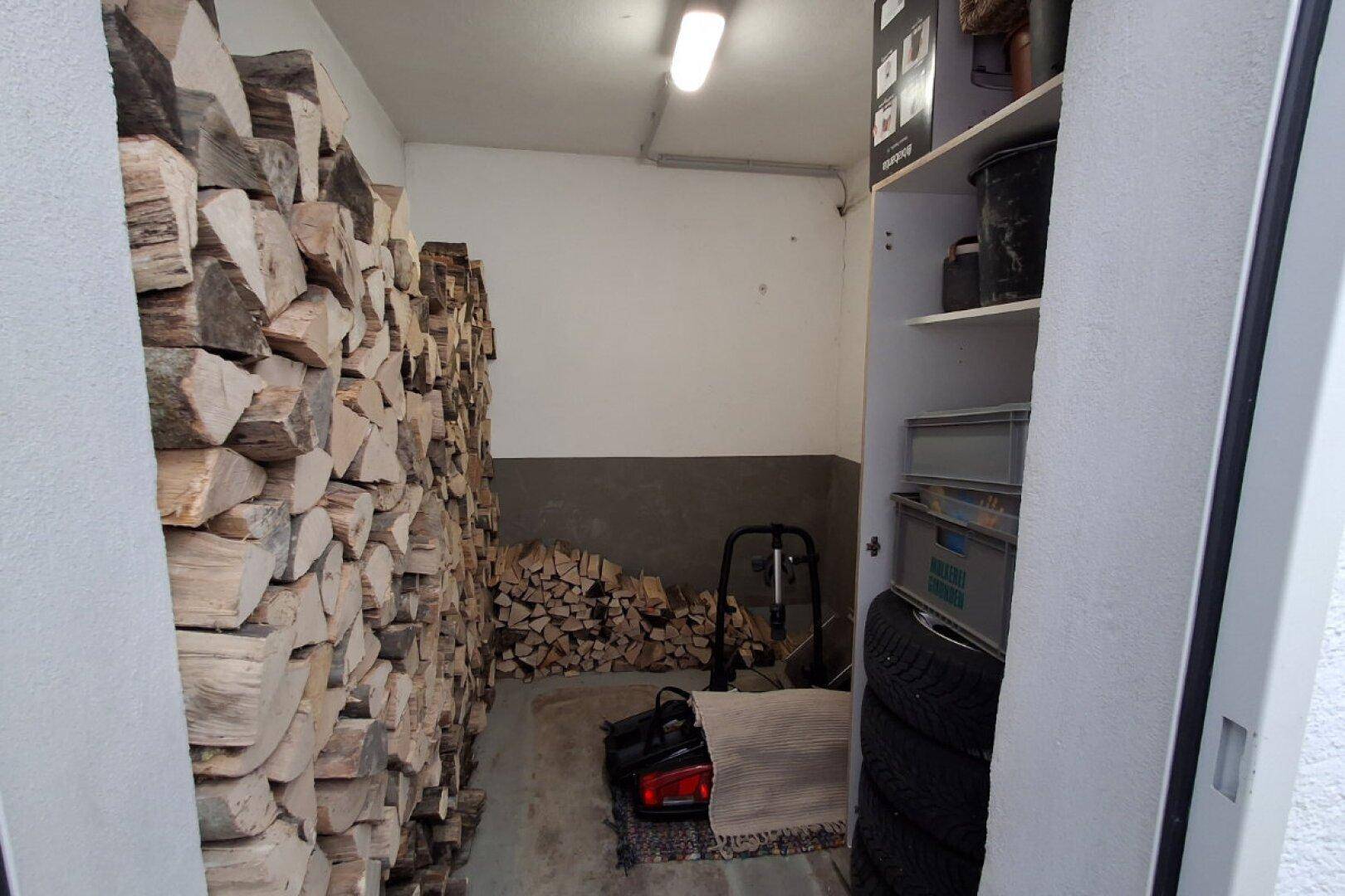 Abstellraum mit gestapeltem Brennholz und Lagerfläche.