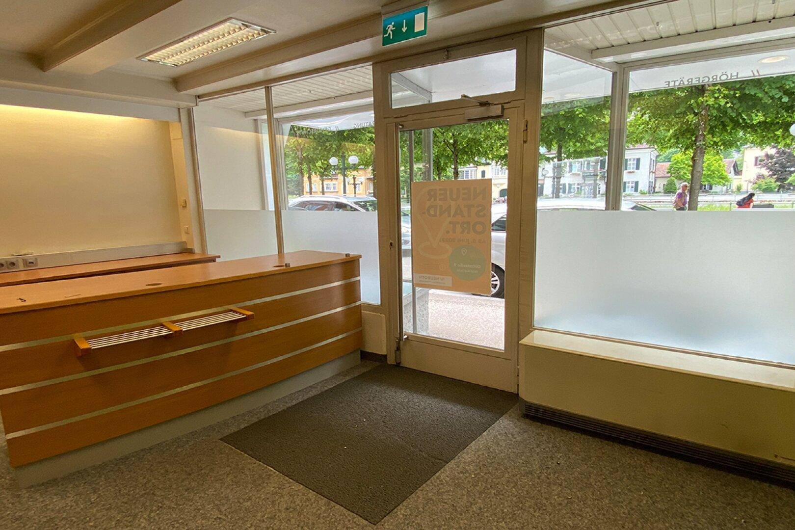 Eingangsbereich eines Geschäftslokals mit Glastür zur Straße und Empfangstheke.
