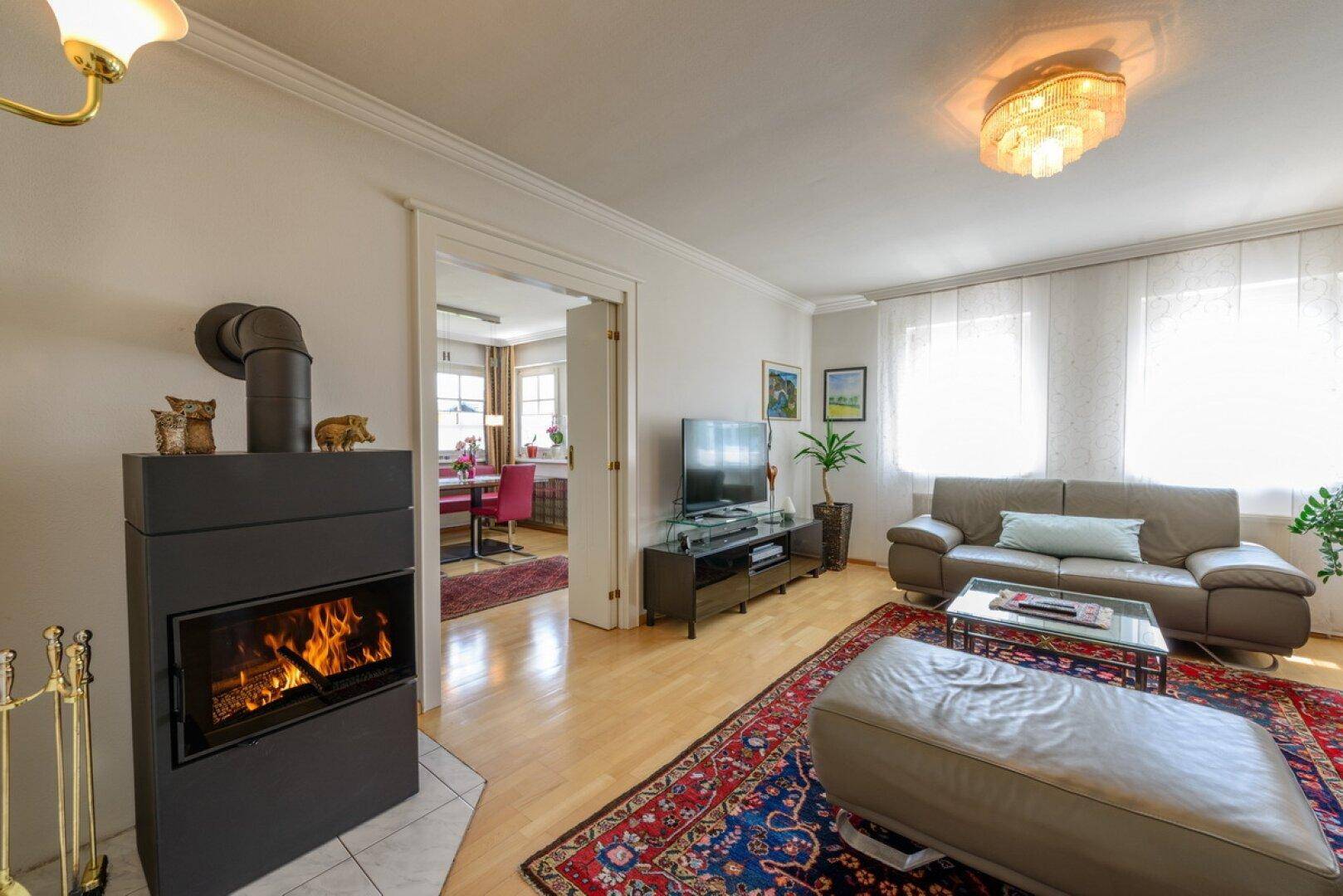 Gemütliches Wohnzimmer mit modernem Holzofen, bequemer Couch und Zugang zum Essbereich.