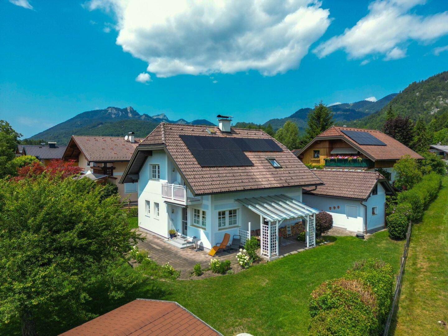 Luftaufnahme des Hauses mit Solaranlage, Garten und der malerischen Berglandschaft im Hintergrund.