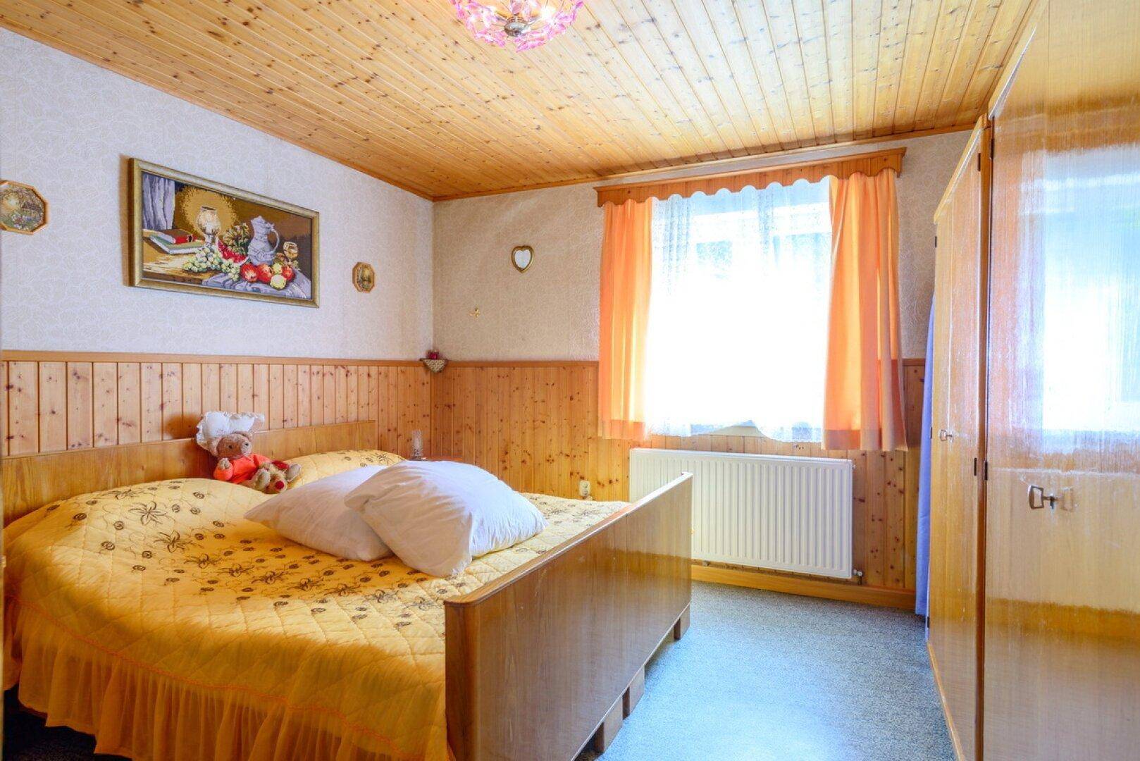 Schlafzimmer mit Doppelbett, Holzvertäfelung und gemütlicher Holzdecke.