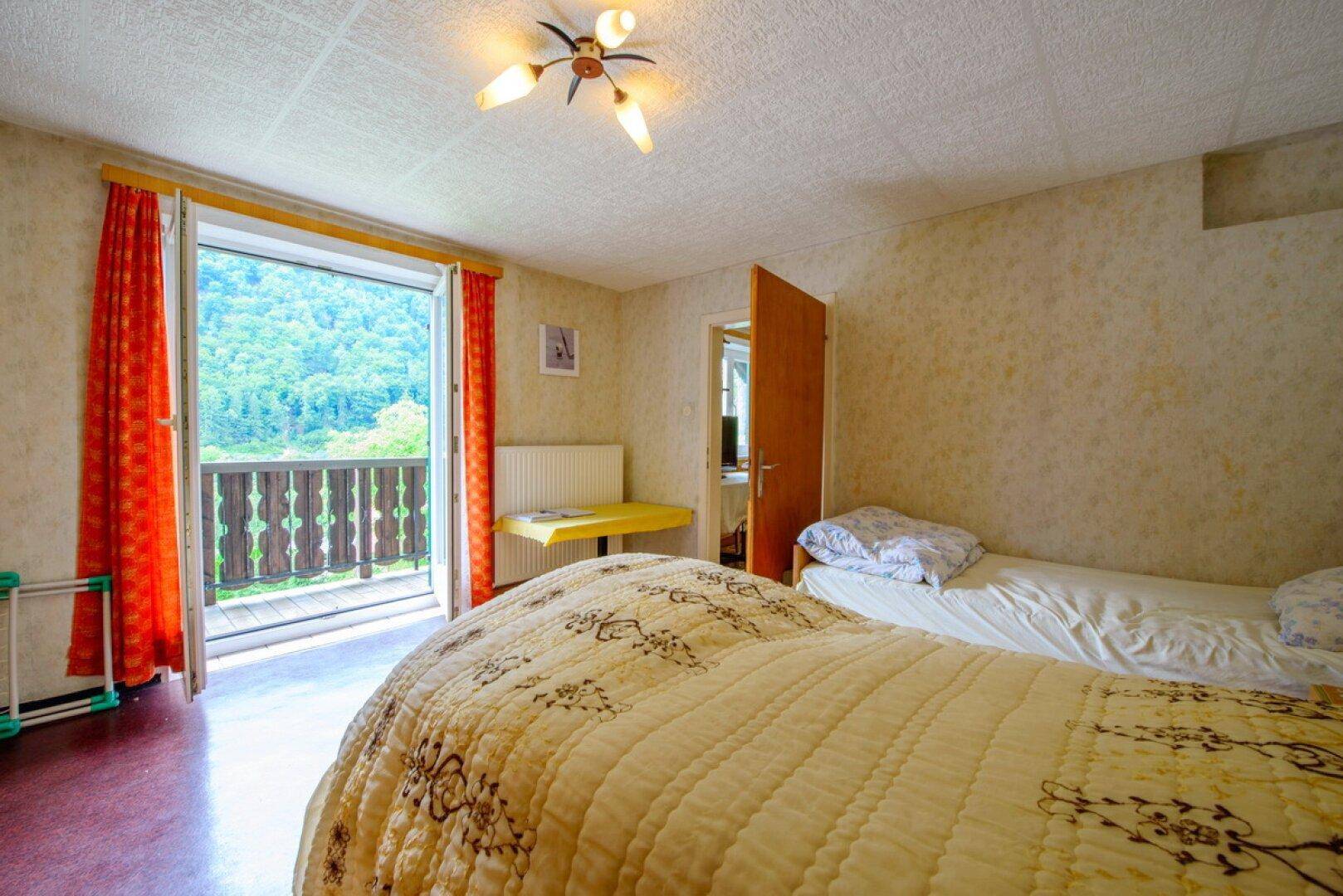 Schlafzimmer mit zwei Einzelbetten und Balkonzugang, bietet einen schönen Bergblick.
