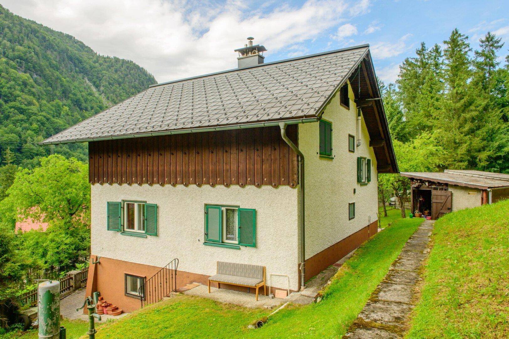 Charmantes Wohnhaus mit traditioneller Architektur und Satteldach, eingebettet in grüne Natur.