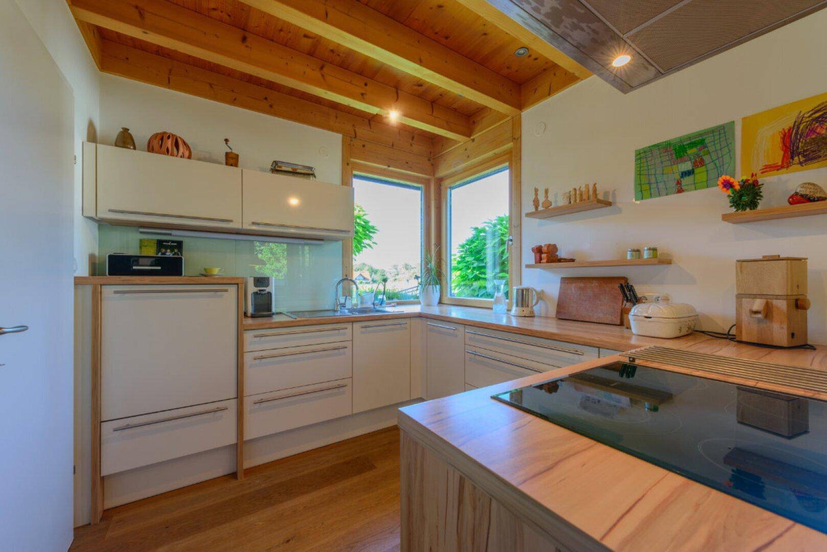 Moderne Einbauküche mit hellen Fronten, Holz-Arbeitsplatten und Induktionskochfeld auf einer Insel.