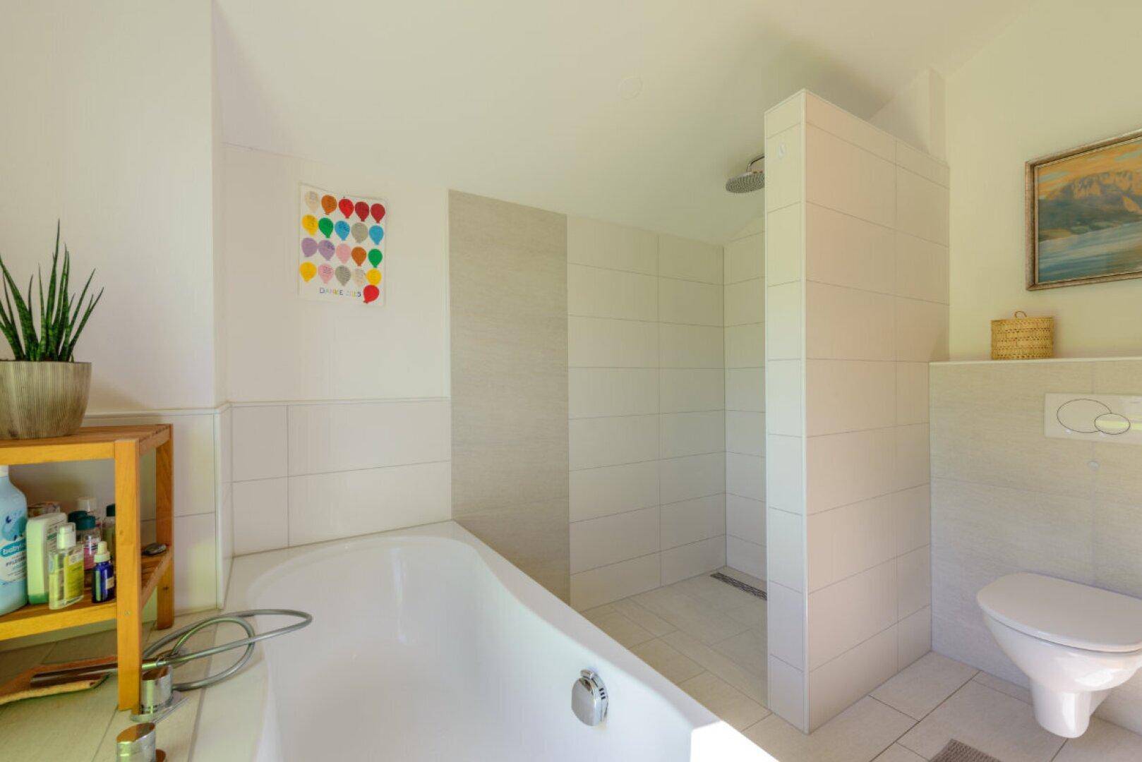 Funktionales Badezimmer mit begehbarer Dusche und wandhängendem WC, hell gefliest und modern gestaltet.