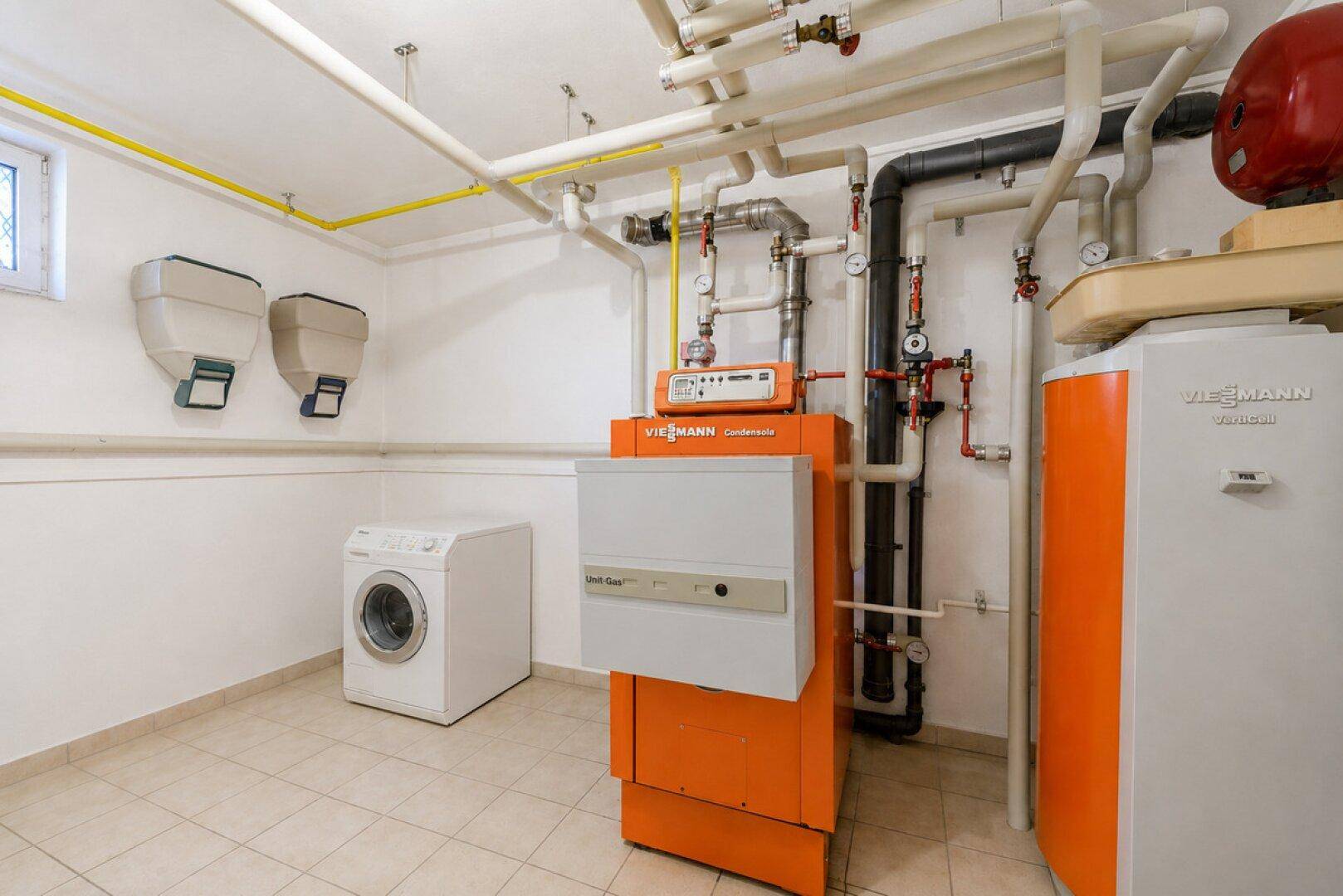 Hauswirtschaftsraum im Keller mit Heizungsanlage, Warmwasserspeicher und Waschmaschine.