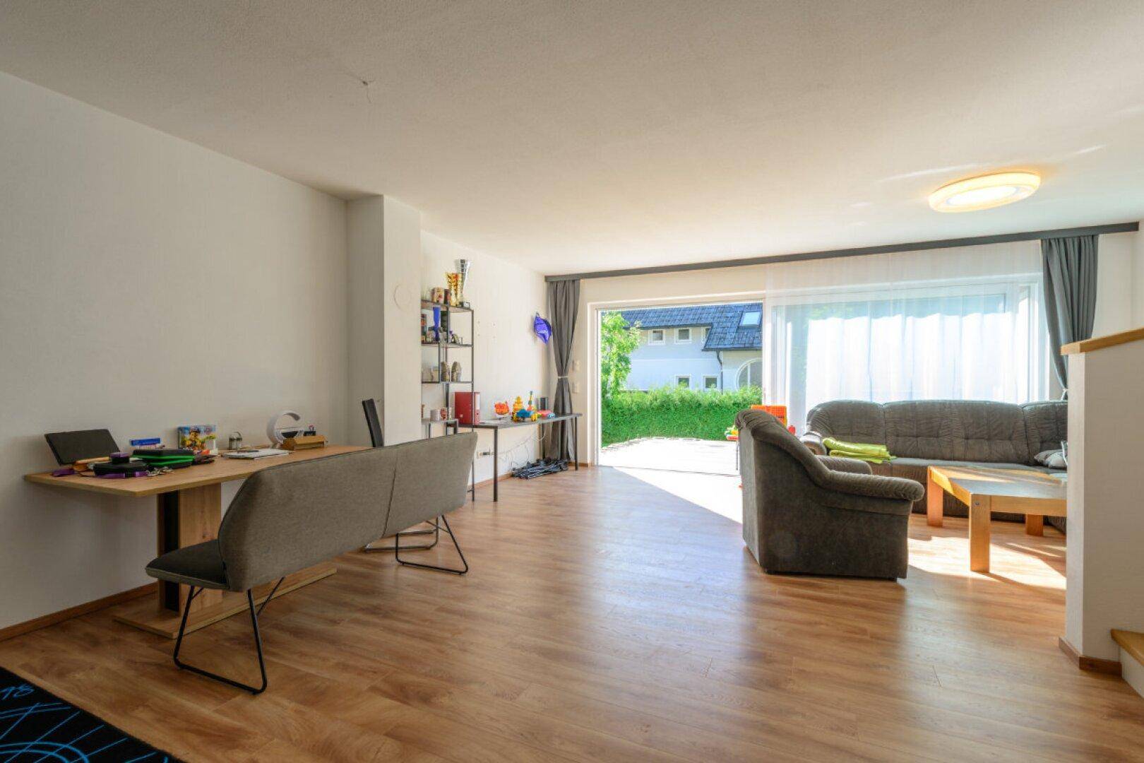 Heller Wohn- und Essbereich mit Zugang zur Terrasse und Blick ins Grüne.
