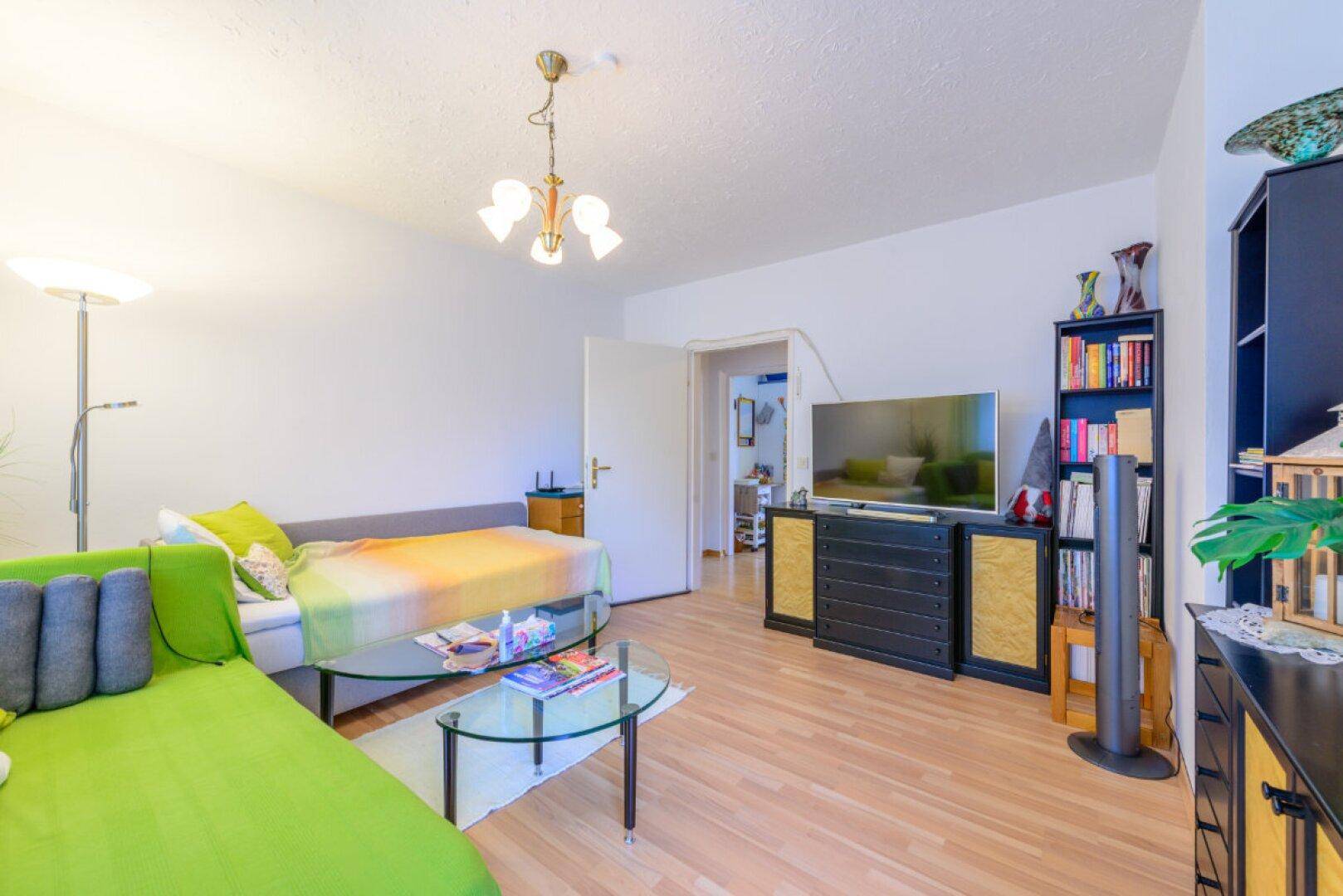 Gemütliches Wohnzimmer mit Tagesbett, Fernseher und Bücherregal, ideal zum Entspannen.