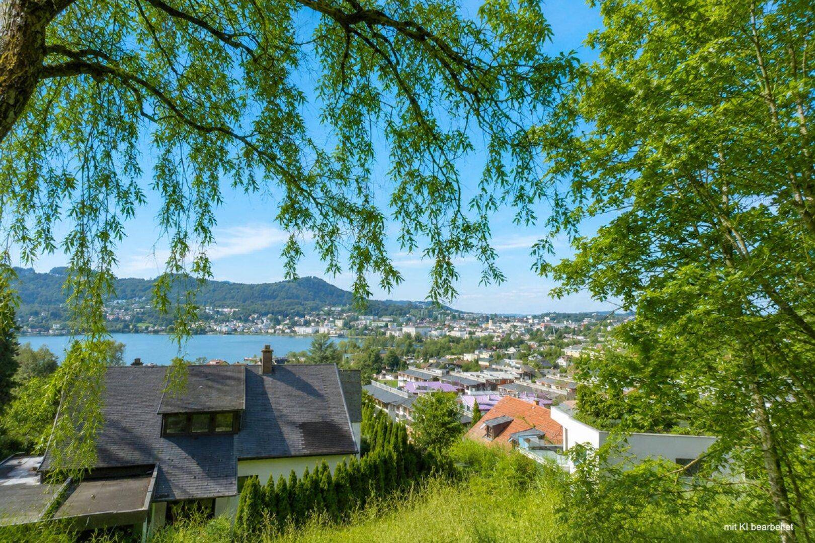 Idyllischer Ausblick auf ein Wohnhaus, umgeben von Bäumen, mit See- und Stadtpanorama.