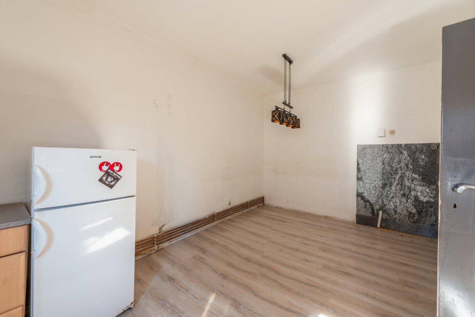 Geräumiger Küchenbereich mit Laminatboden und einem Kühlschrank, bereit für eine Neugestaltung.
