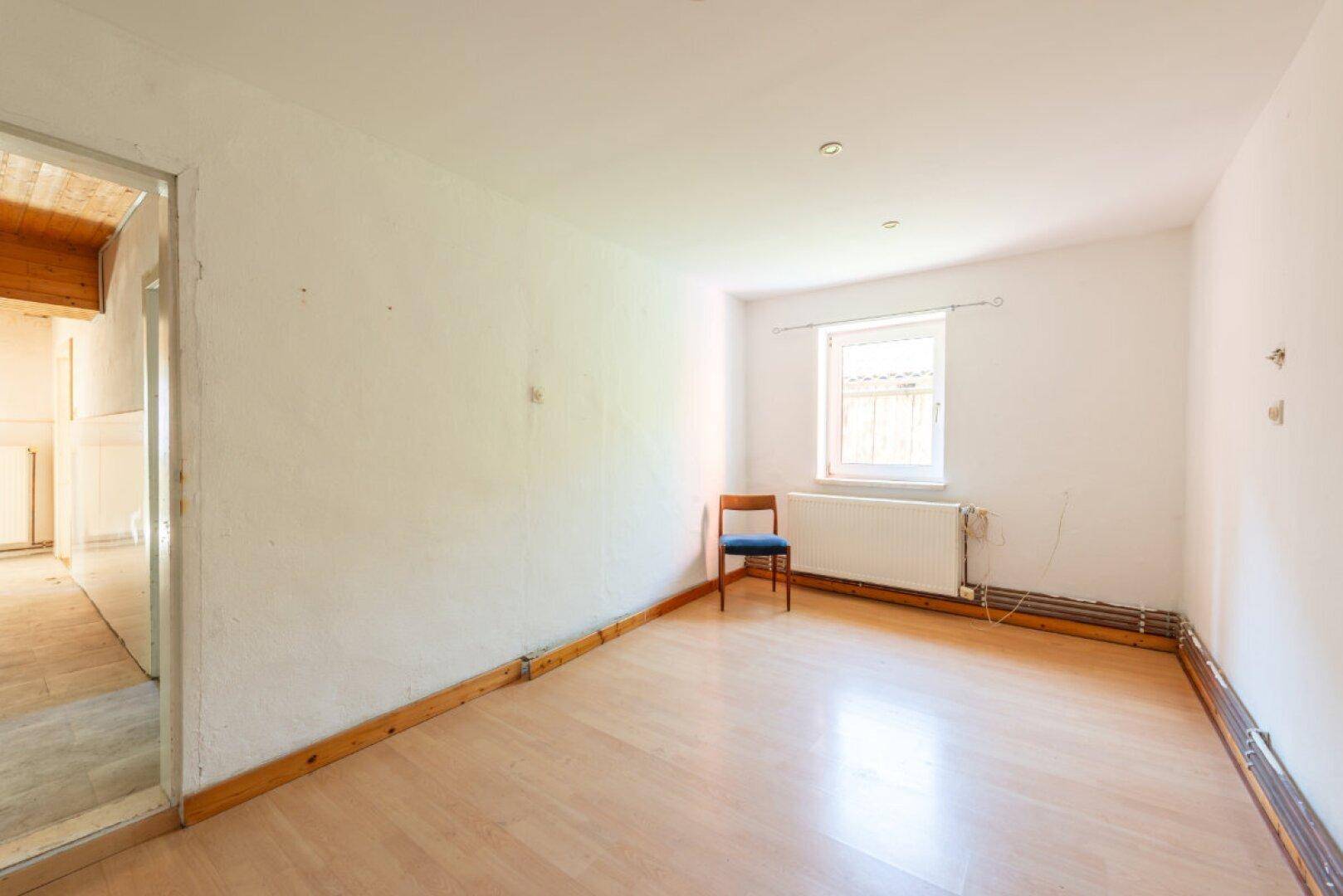 Heller Raum mit hellem Holzboden, Fenster und Heizkörper, ideal als Wohn- oder Schlafzimmer.
