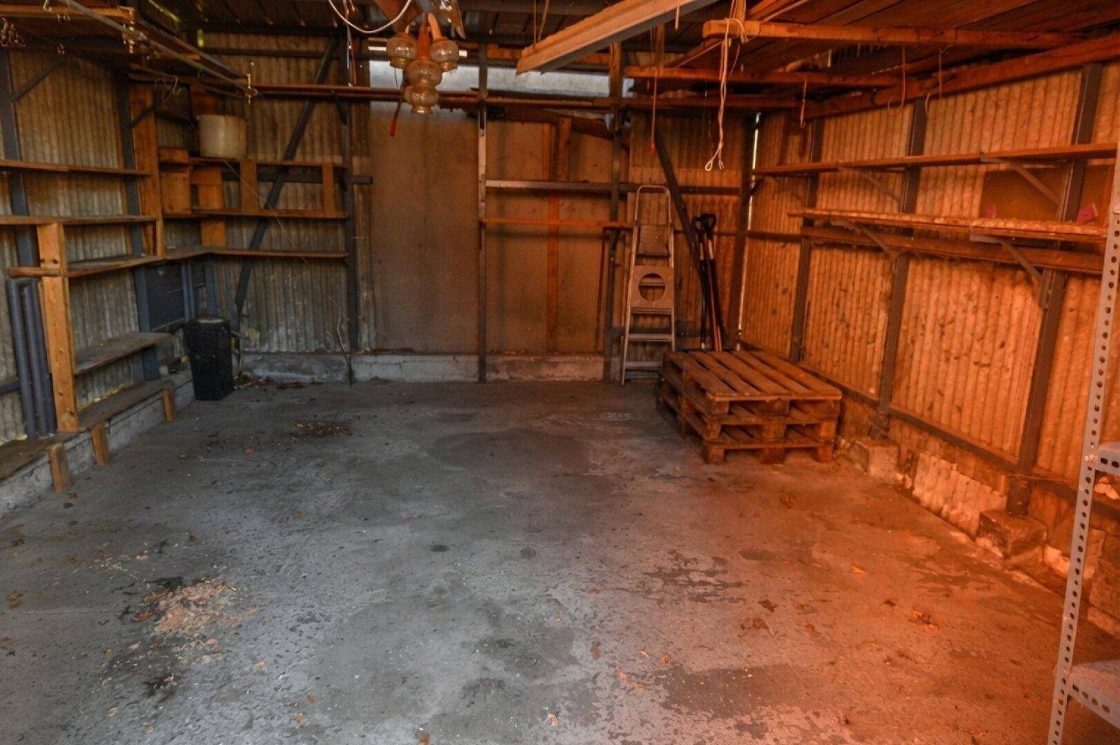 Innenansicht der Garage mit Betonboden, Regalen und Lagerfläche.