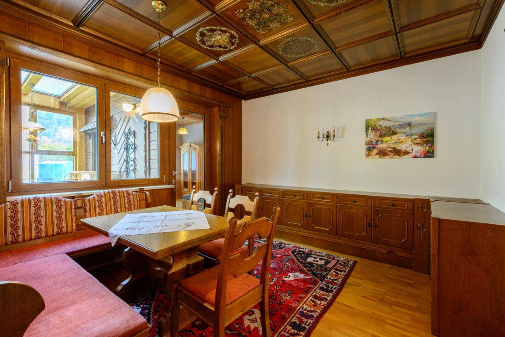 Esszimmer mit Holztäfelung, Kassettendecke und traditionellem Esstisch mit Eckbank.