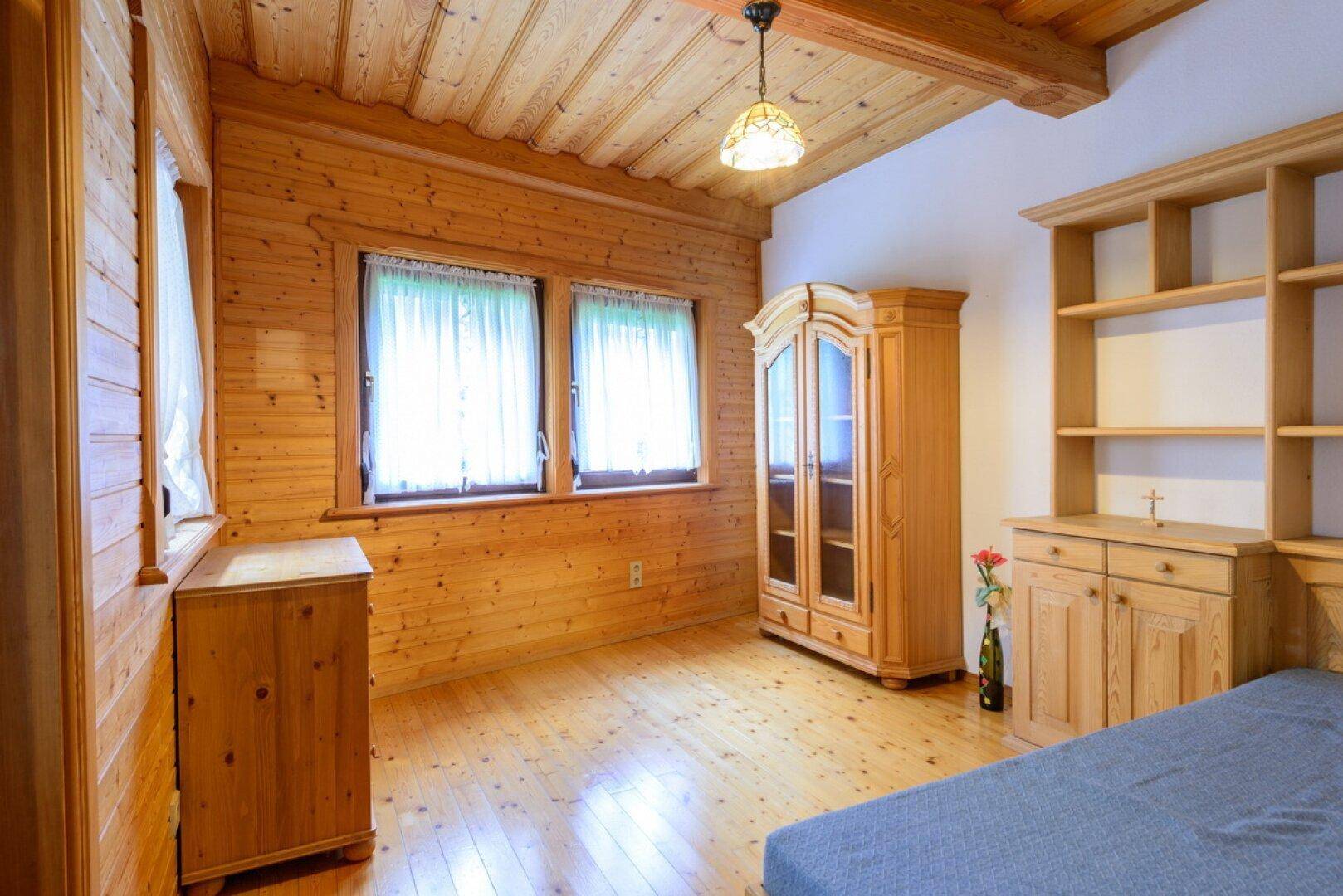 Rustikales Schlafzimmer mit Holzvertäfelung, Holzboden und traditionellen Holzmöbeln.