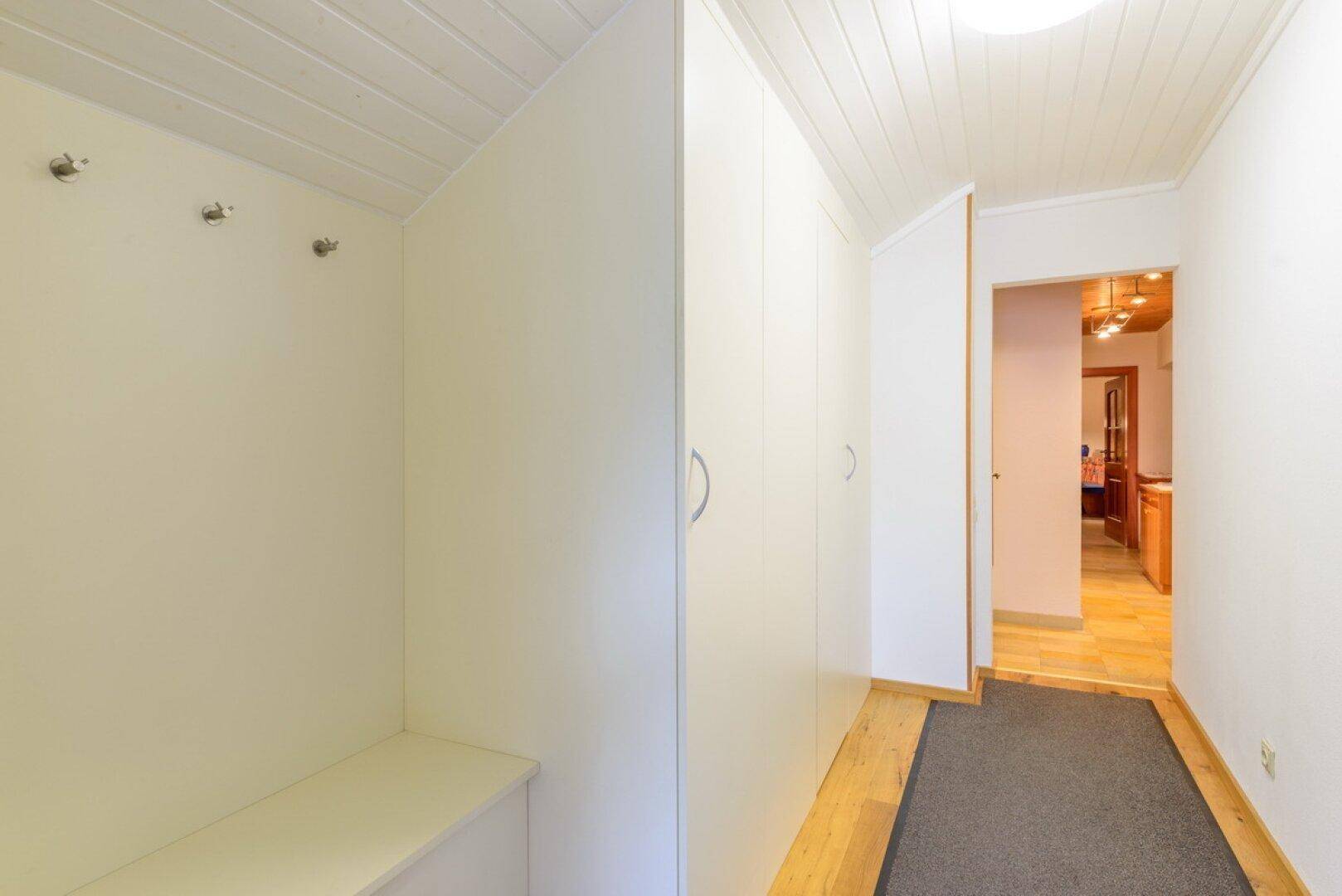 Eingangsbereich mit Garderobe, Einbauschränken und hellem Holzboden.