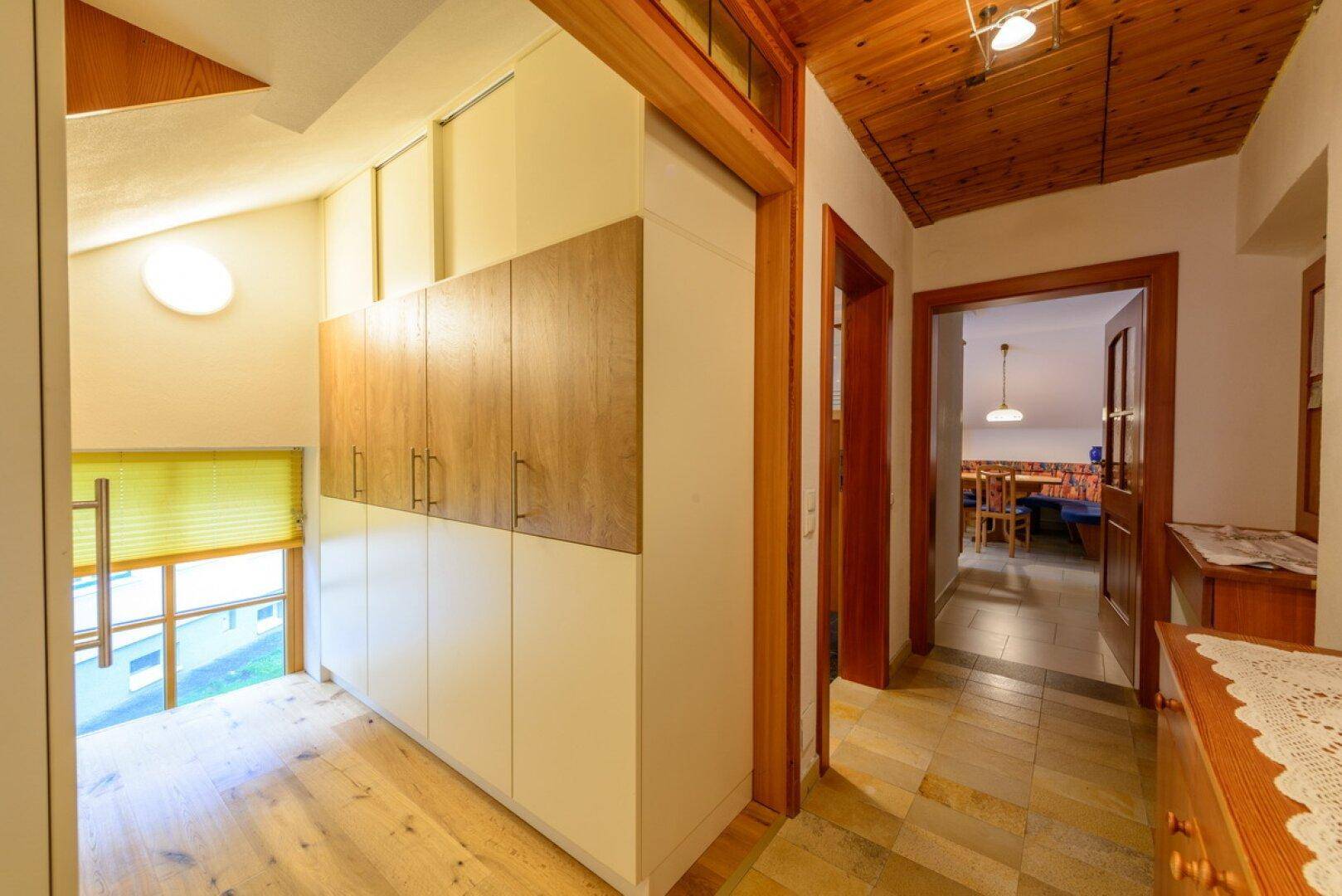 Heller Flur mit Holzboden, Einbauschränken und Blick in angrenzende Räume.