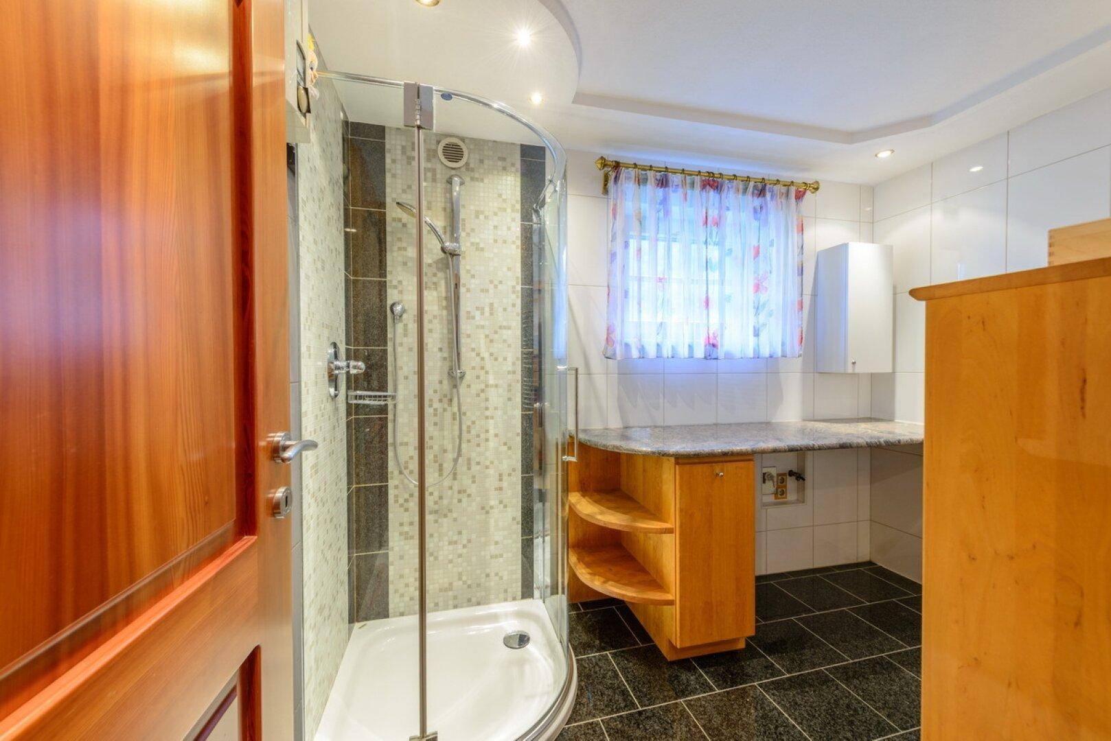 Badezimmer mit Duschkabine, Fliesenboden und Fenster für natürliche Belüftung.
