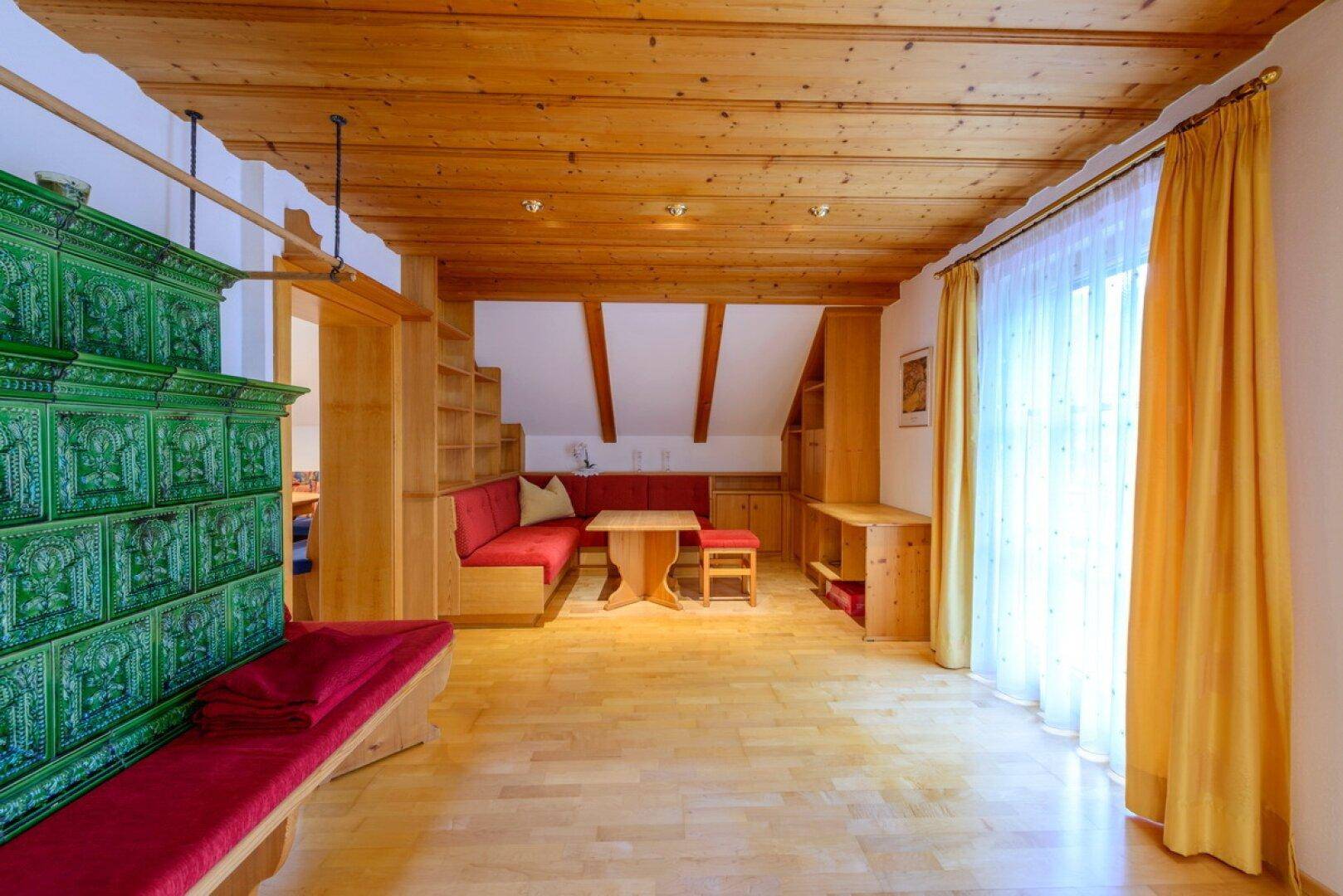 Heller Wohnbereich mit Holzbalkendecke, Parkettboden und integrierten Holzmöbeln unter Dachschrägen.