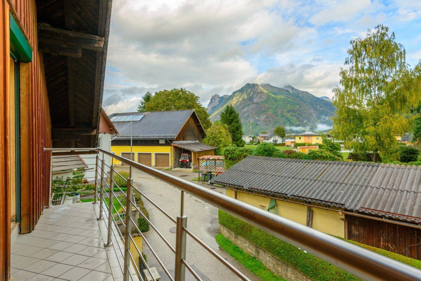 Balkon mit Metallgeländer und Blick auf die umliegende Berglandschaft und Nachbarschaft.