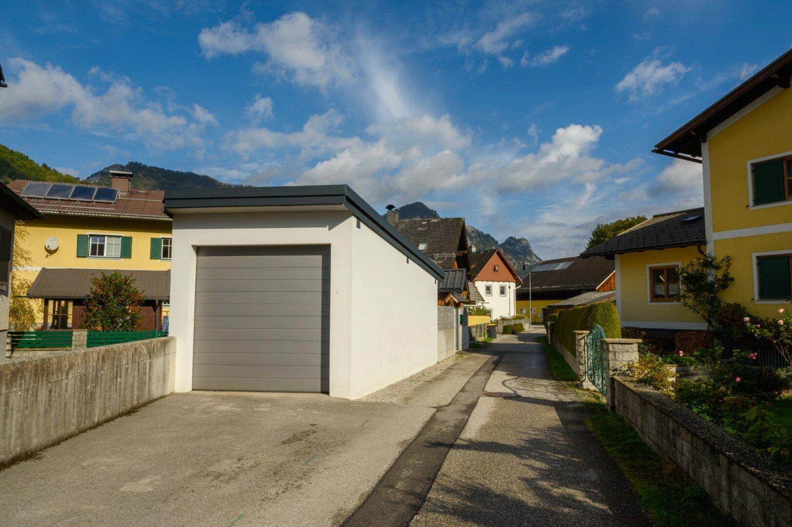 Moderne Garage mit Rolltor an einer ruhigen Wohnstraße, umgeben von Häusern.