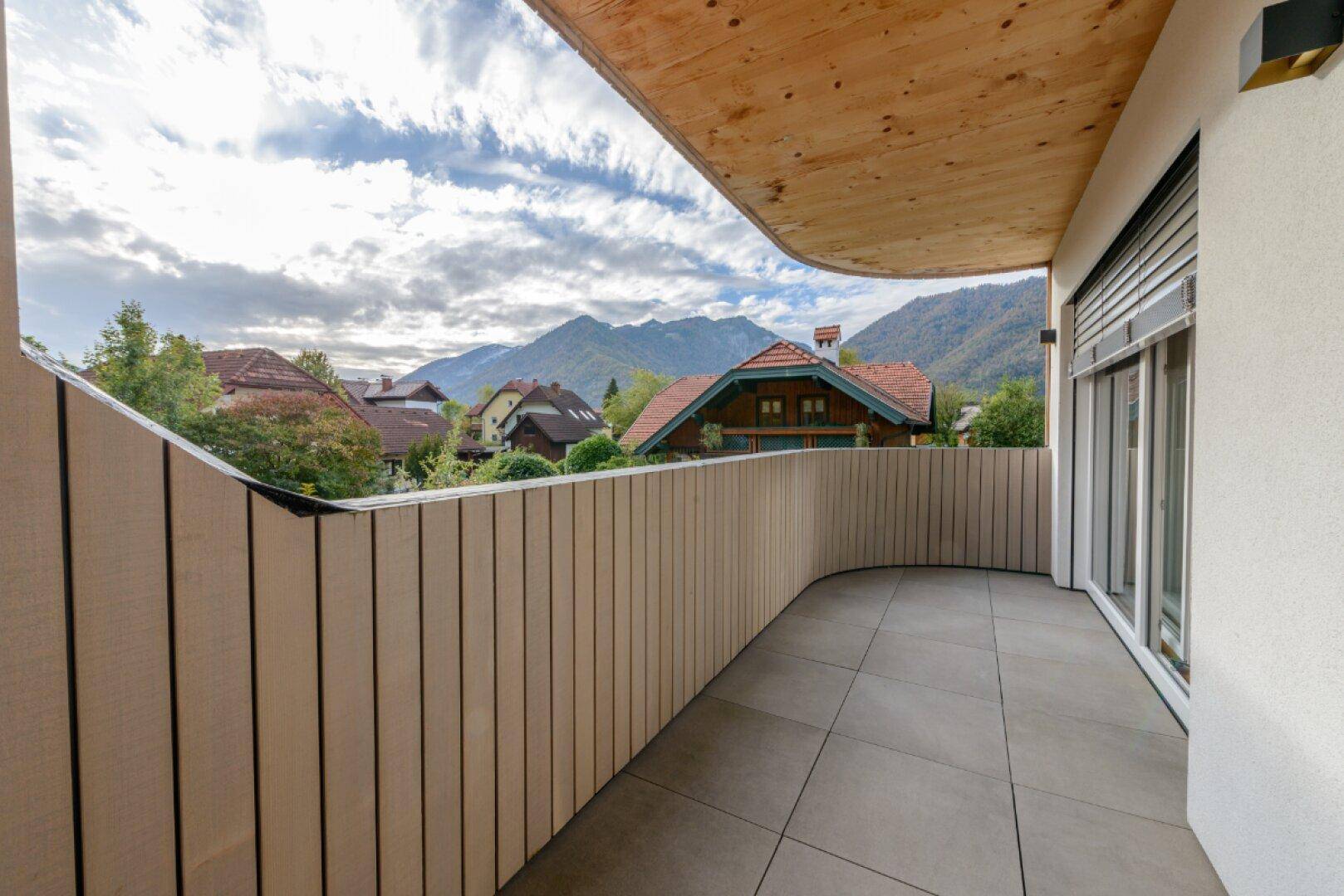 Geräumiger Balkon mit Holzwänden und Fliesenboden, bietet Bergblick und frische Luft.