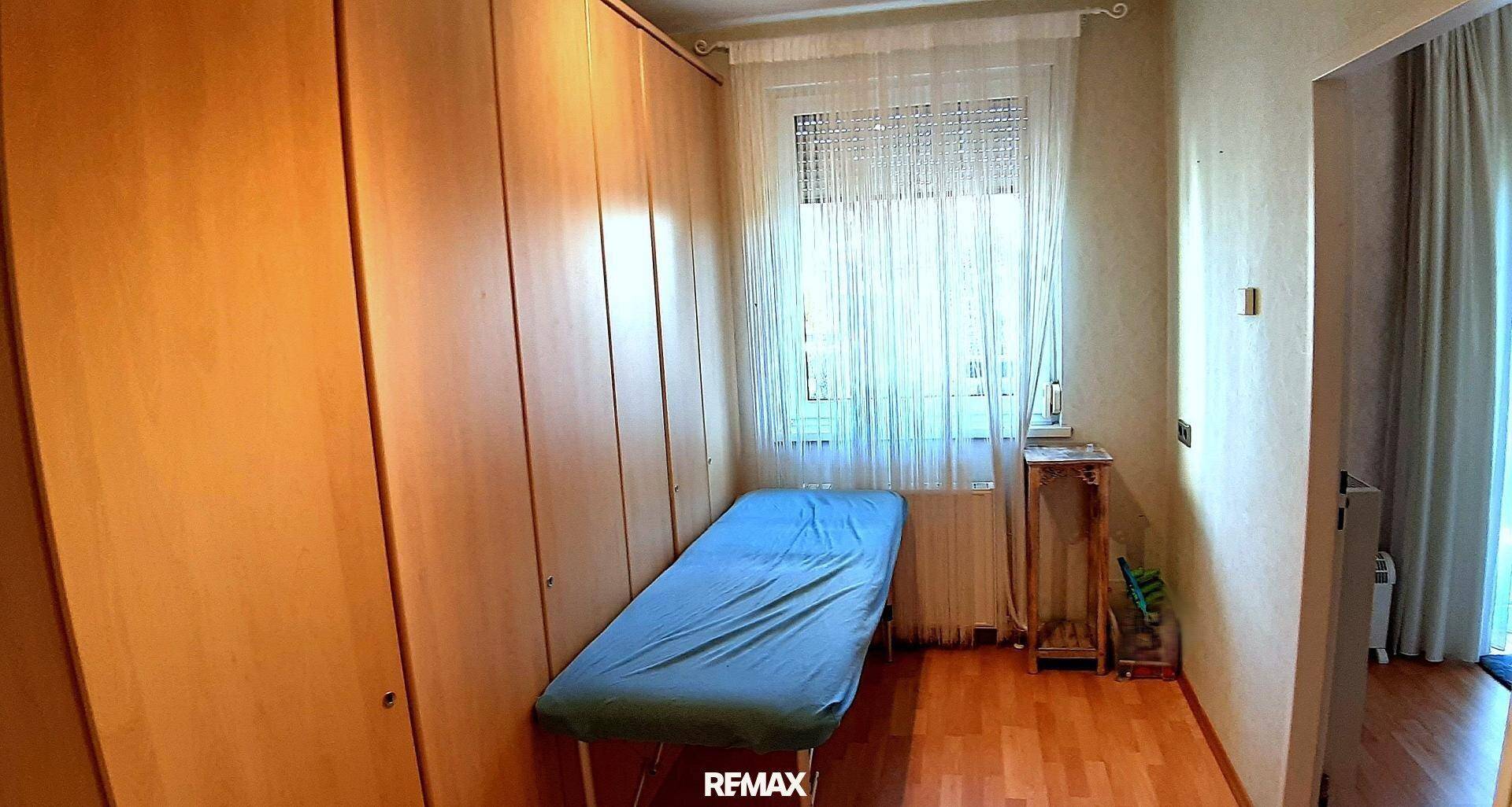 Kleines Zimmer mit integrierten Einbauschränken, Holzboden und einem Fenster, das Tageslicht hereinlässt.
