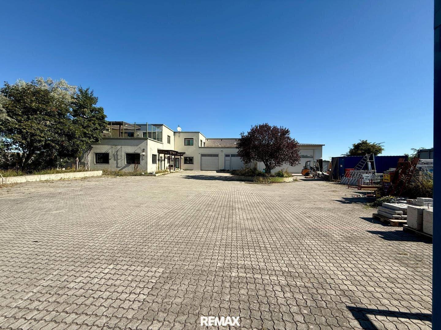 Weitläufiger Außenbereich mit gepflastertem Parkplatz und einem modernen Geschäftsgebäude im Hintergrund.
