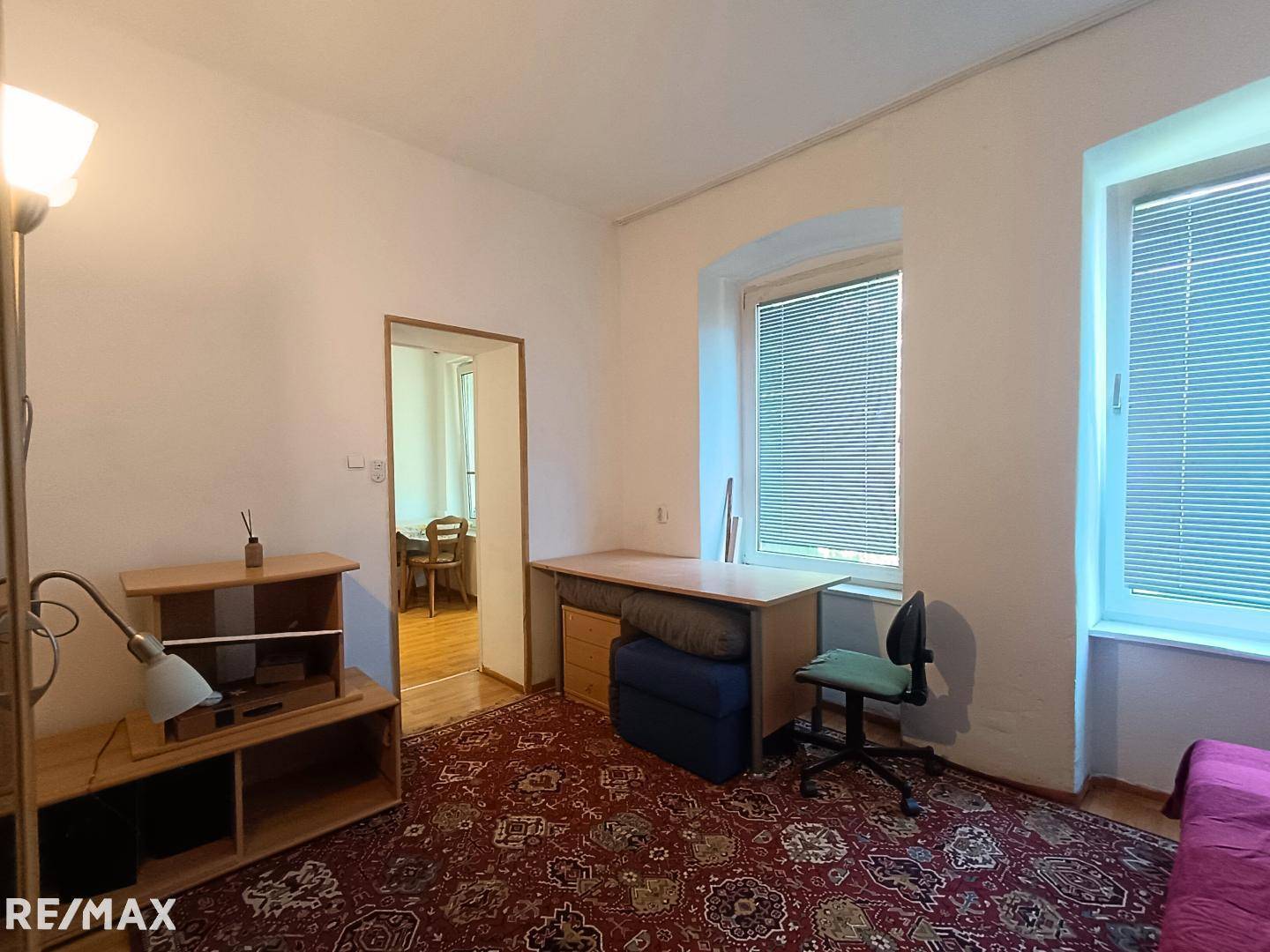 Geräumiges Schlafzimmer mit Teppichboden, Schreibtisch und zwei großen Fenstern.