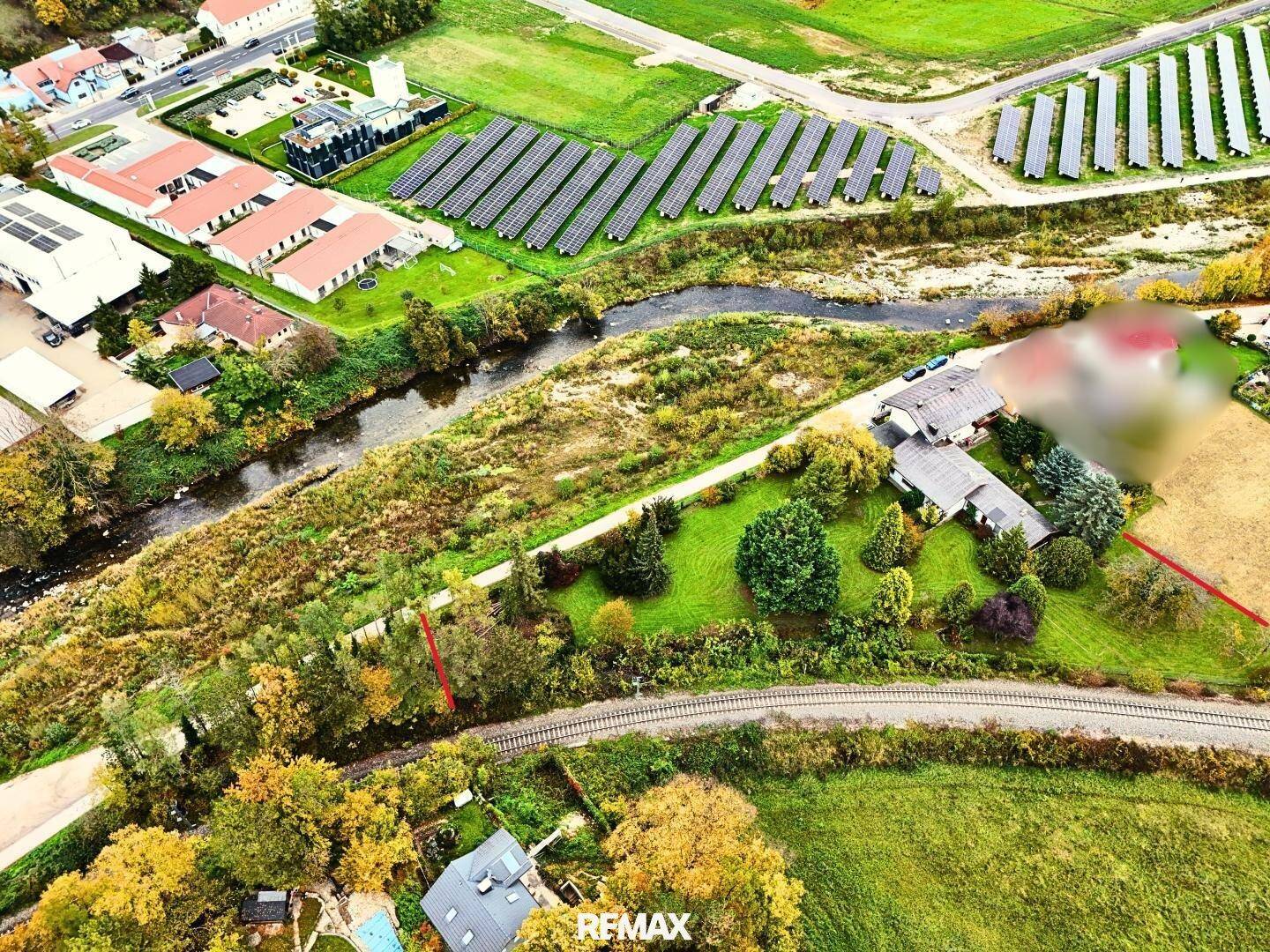 Weitläufige Luftaufnahme des Anwesens mit Fluss, Bahngleisen und angrenzenden Solaranlagen in der Landschaft.
