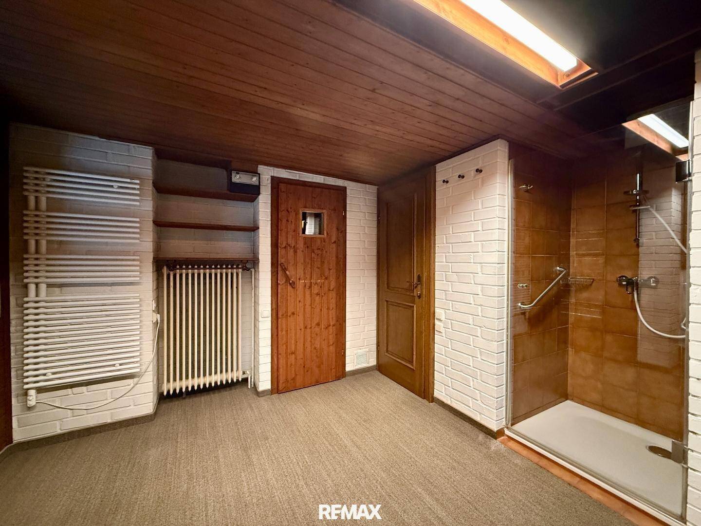 Wellnessbereich mit Duschkabine, Handtuchheizkörper und Zugang zur Sauna.