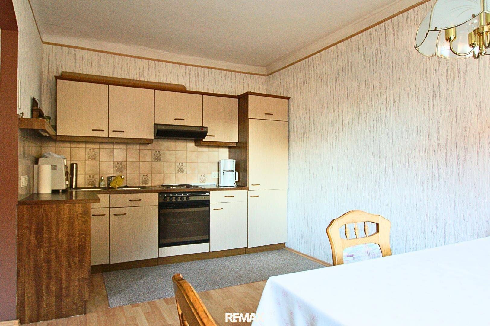 Traditionelle Küche mit beigen Einbauschränken, Fliesenrückwand und Essbereich.