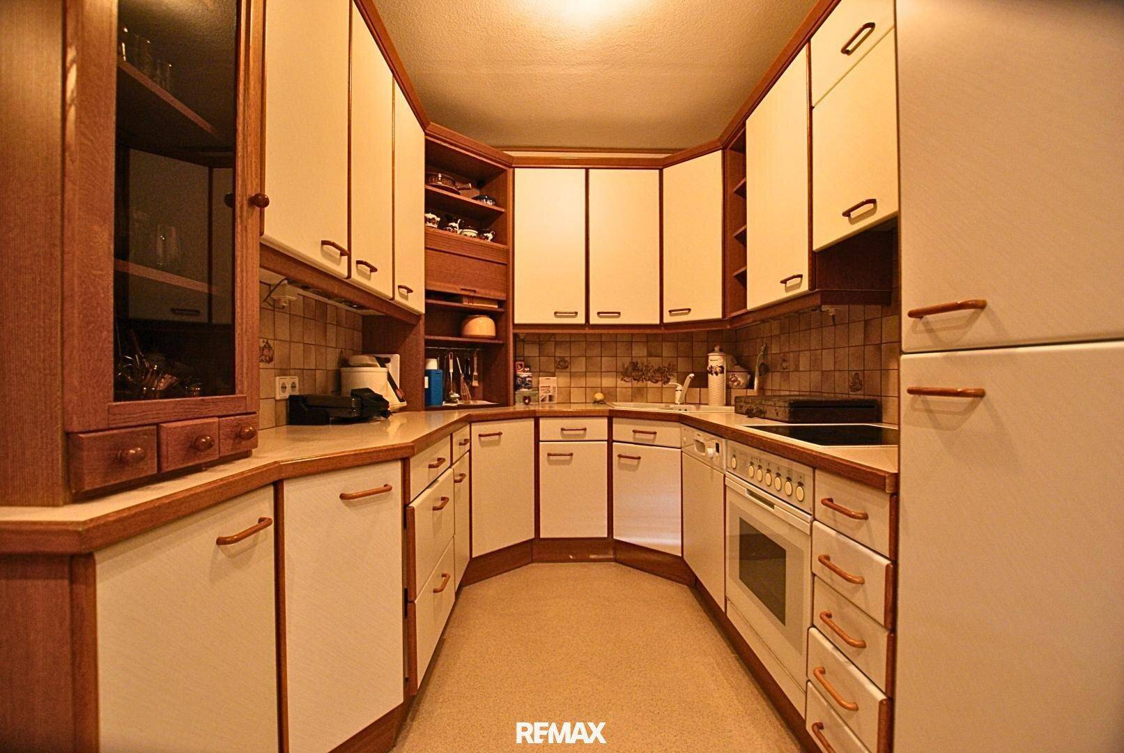 Funktionale Küche mit vielen Ober- und Unterschränken und integriertem Backofen.