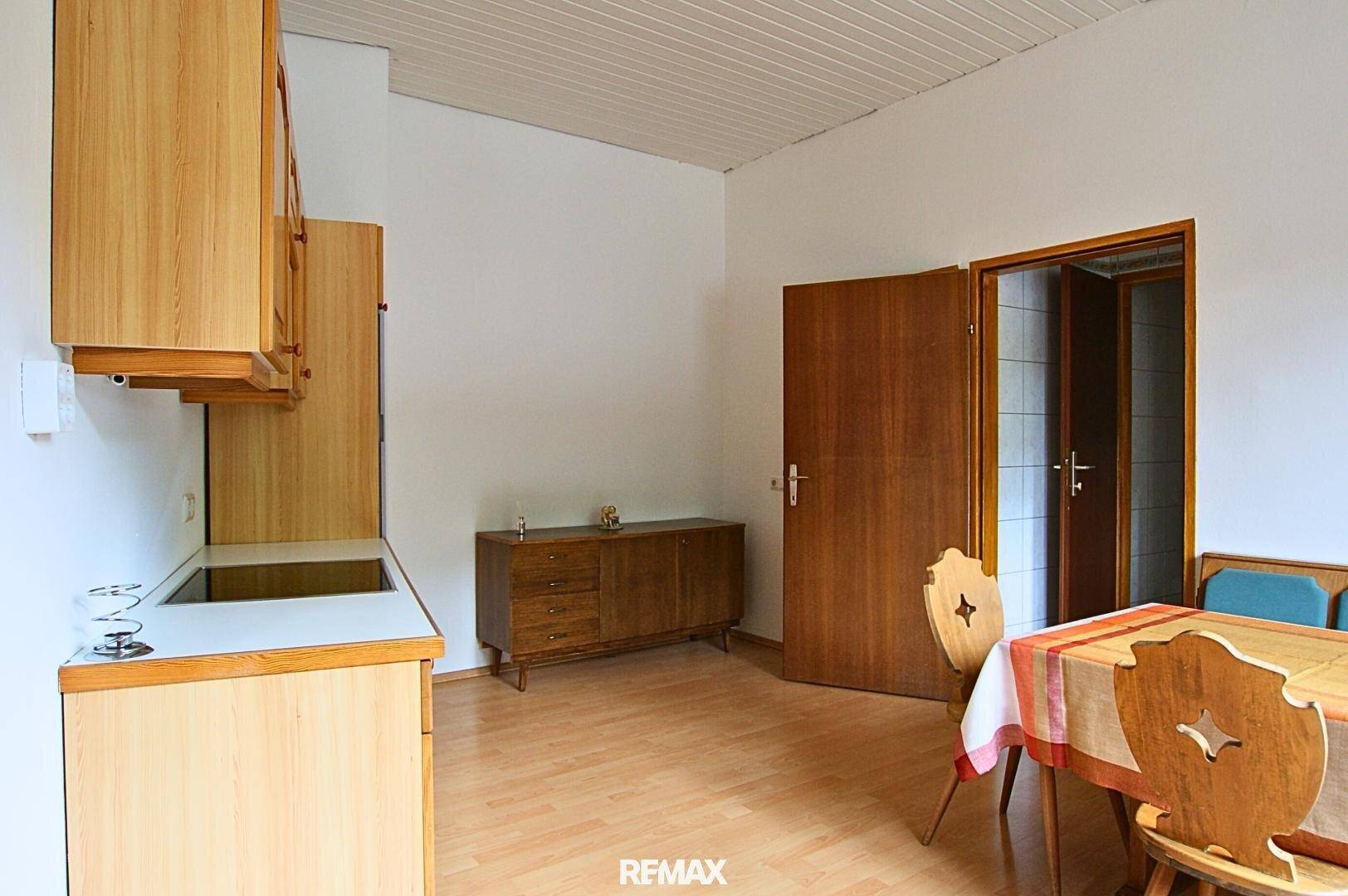 Traditionelle Küche mit Holzschränken, Laminatboden und einem Essbereich mit rustikalen Stühlen.