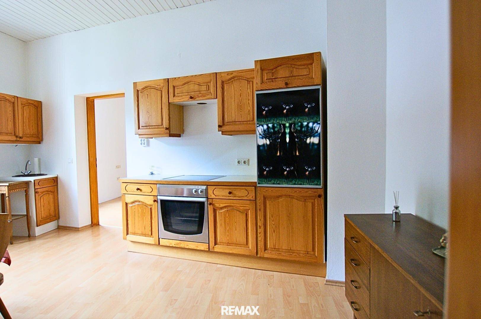 Traditionelle Küche mit Holzschränken, Einbauherd und einem dekorativen Vitrinenschrank.