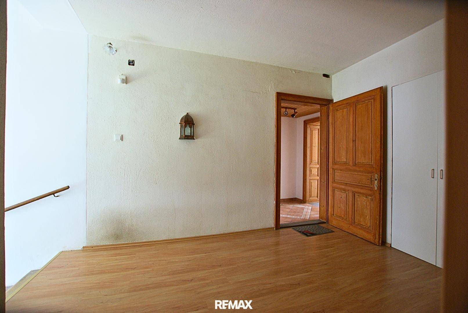Geräumiger Flur mit Holzboden, weiß gestrichenen Wänden und einer eingebauten Garderobe.