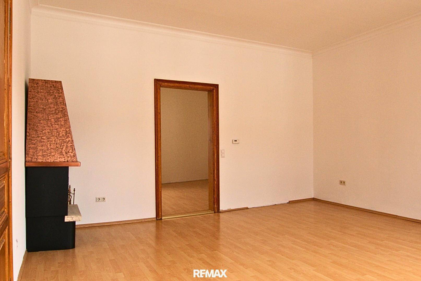 Heller Raum mit Holzboden und einem Kamin, der eine gemütliche Atmosphäre schafft.