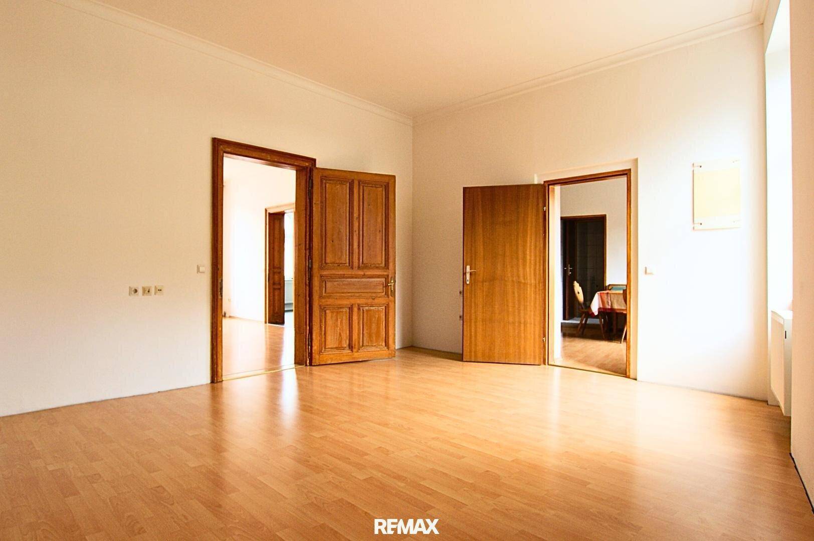 Geräumiger Raum mit Holzboden und mehreren Holztüren, die verschiedene Bereiche verbinden.