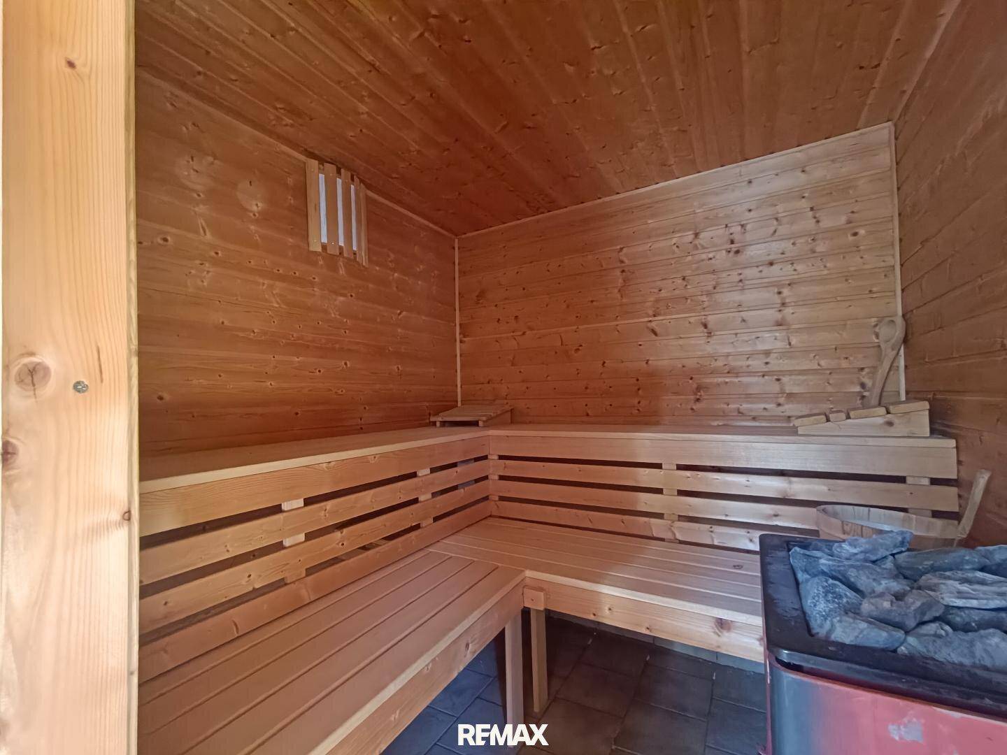 Traditionelle Holzsauna mit mehreren Bänken und einem Saunaofen, ideal für Entspannung und Wellness.