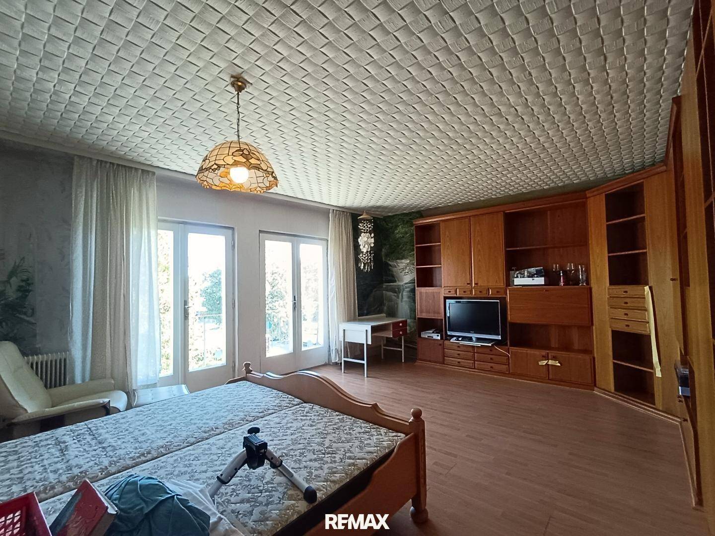 Geräumiges Schlafzimmer mit Doppelbett, Holzmöbeln und Zugang zu einem Balkon durch große Fenster.