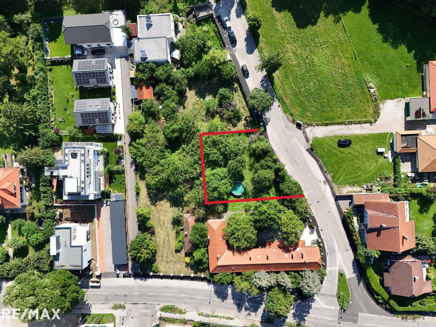 Übersichtliche Luftaufnahme des Grundstücks mit roter Umrandung, umgeben von Einfamilienhäusern und viel Natur.