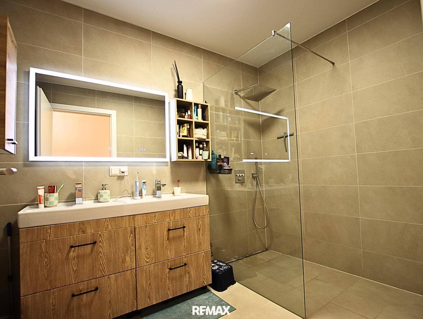 Modernes Badezimmer mit großformatigen Fliesen, begehbarer Dusche und stilvollem Waschtisch.