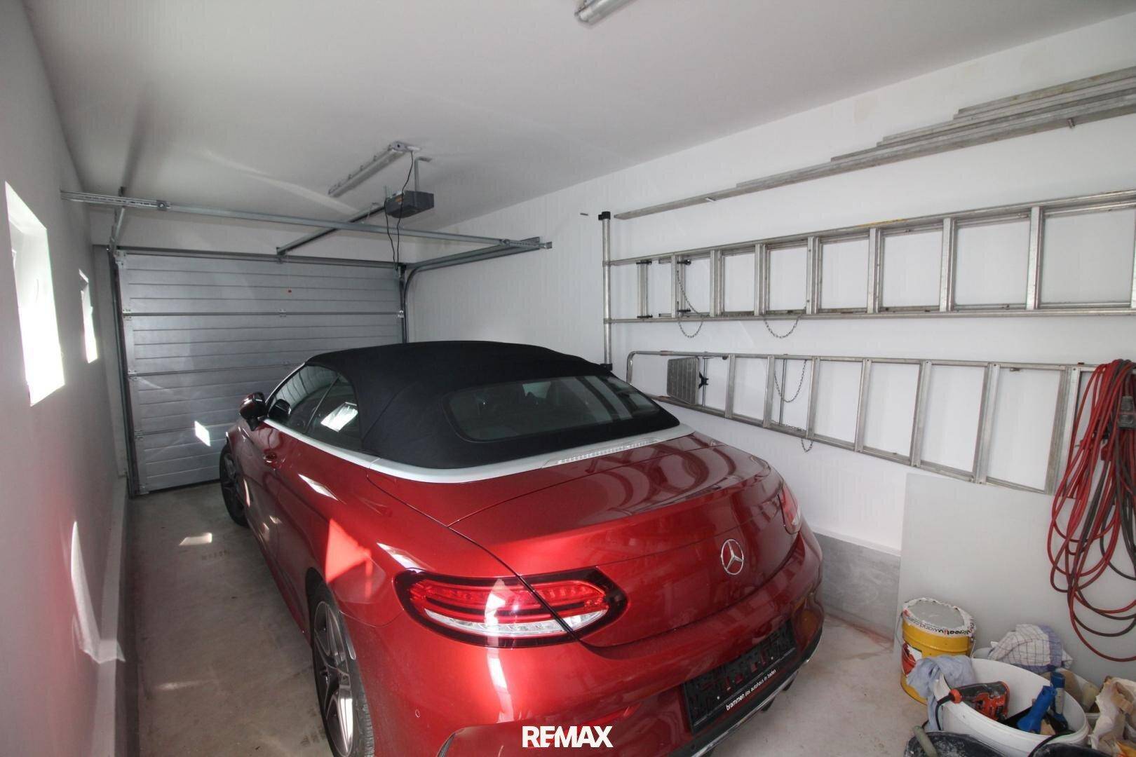 Geräumige Garage mit einem roten Cabrio und praktischen Lagerregalen an der Wand.