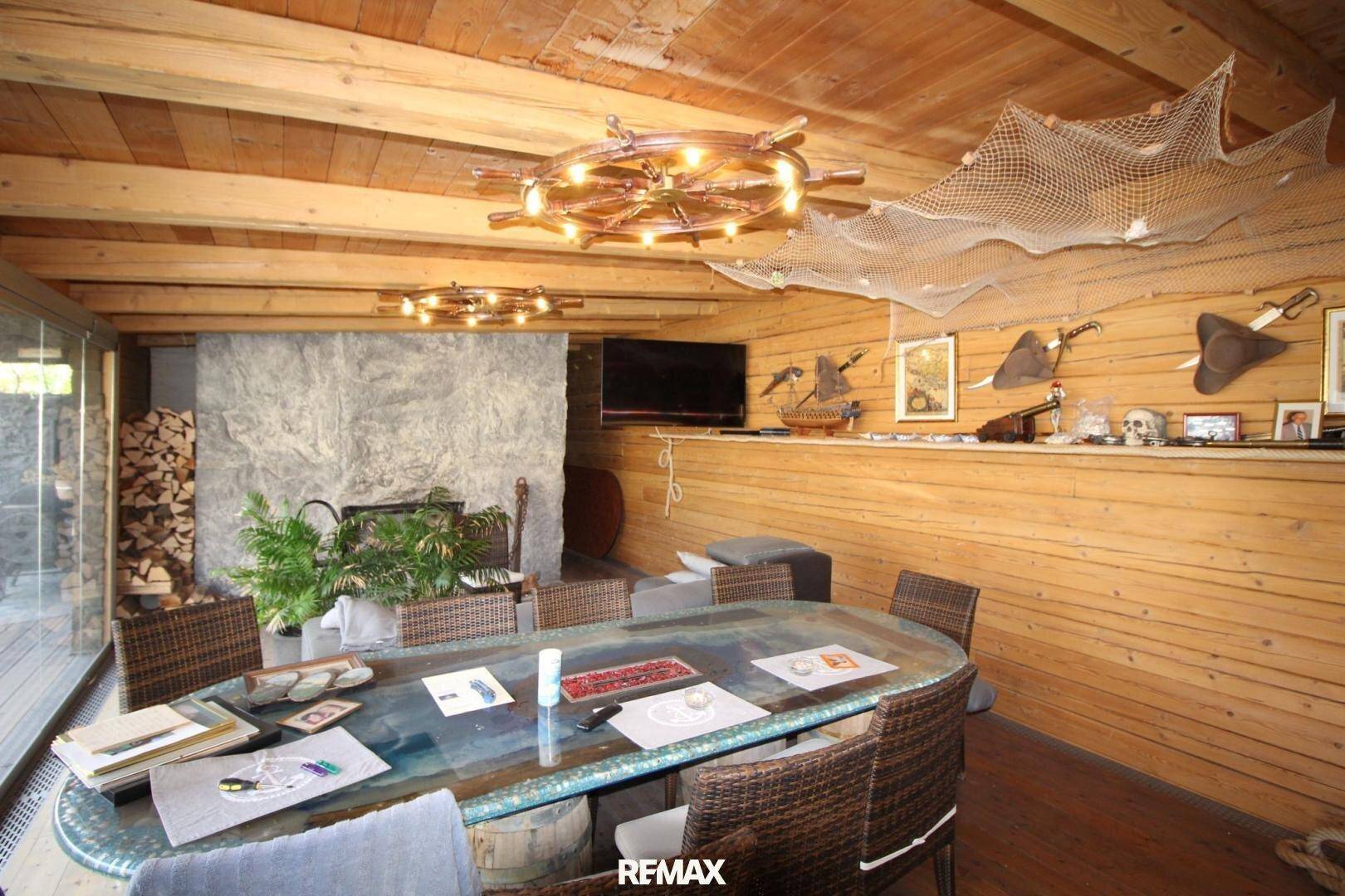 Geräumiger Wohn- und Essbereich im alpinen Stil mit Holzwänden, großem Tisch und Kamin.