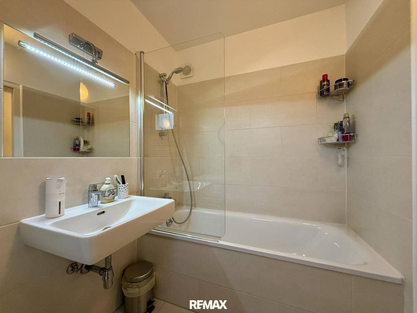 Helles Badezimmer mit Badewanne, Duschabtrennung und modernem Waschtisch.
