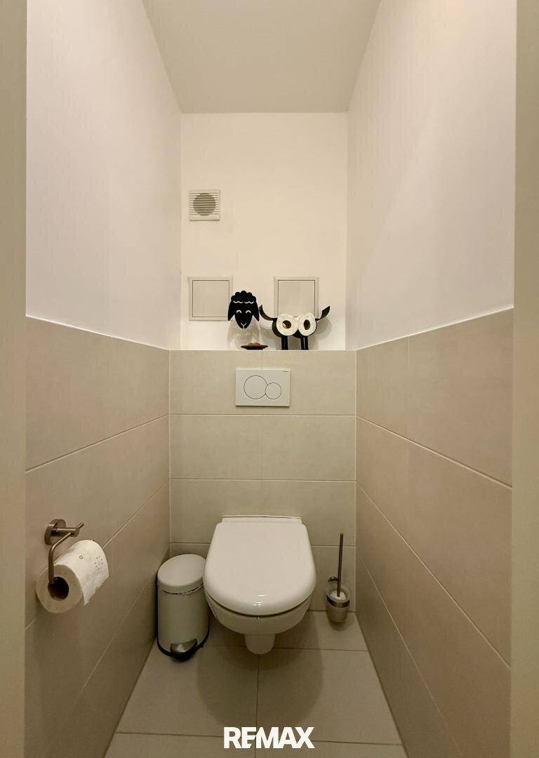 Kleines, separates WC mit Wand-WC, Fliesenboden und minimalistischer Dekoration.
