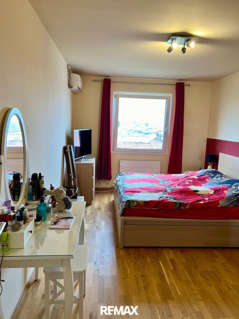 Gemütliches Schlafzimmer mit Holzboden, Doppelbett, Schminktisch und Klimaanlage.