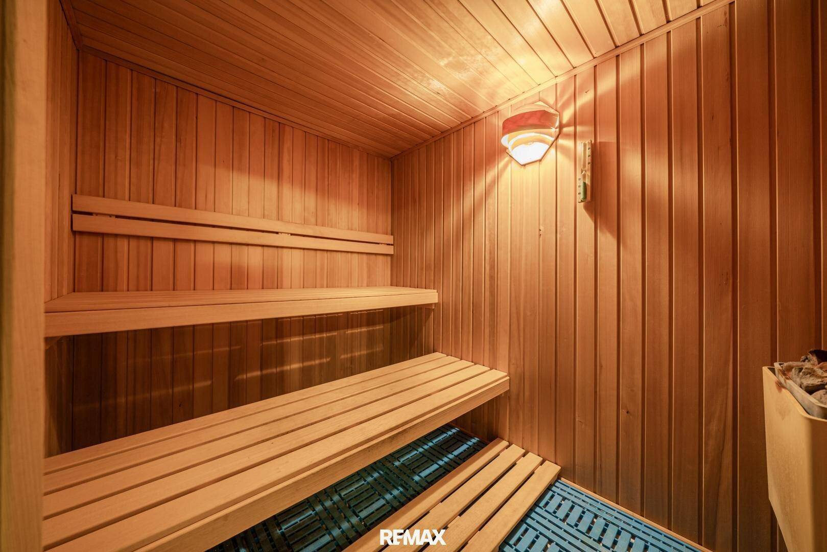 Gemütliche Holzsauna mit mehreren Bänken und stimmungsvoller Beleuchtung.