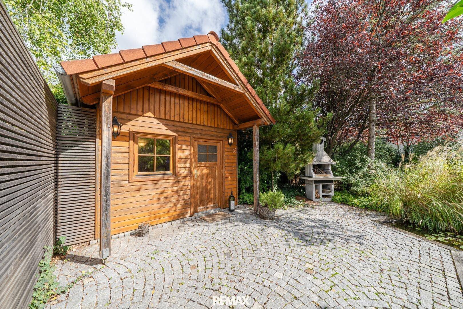 Charmantes Gartenhaus mit Grillplatz und gepflastertem Bereich im Grünen.