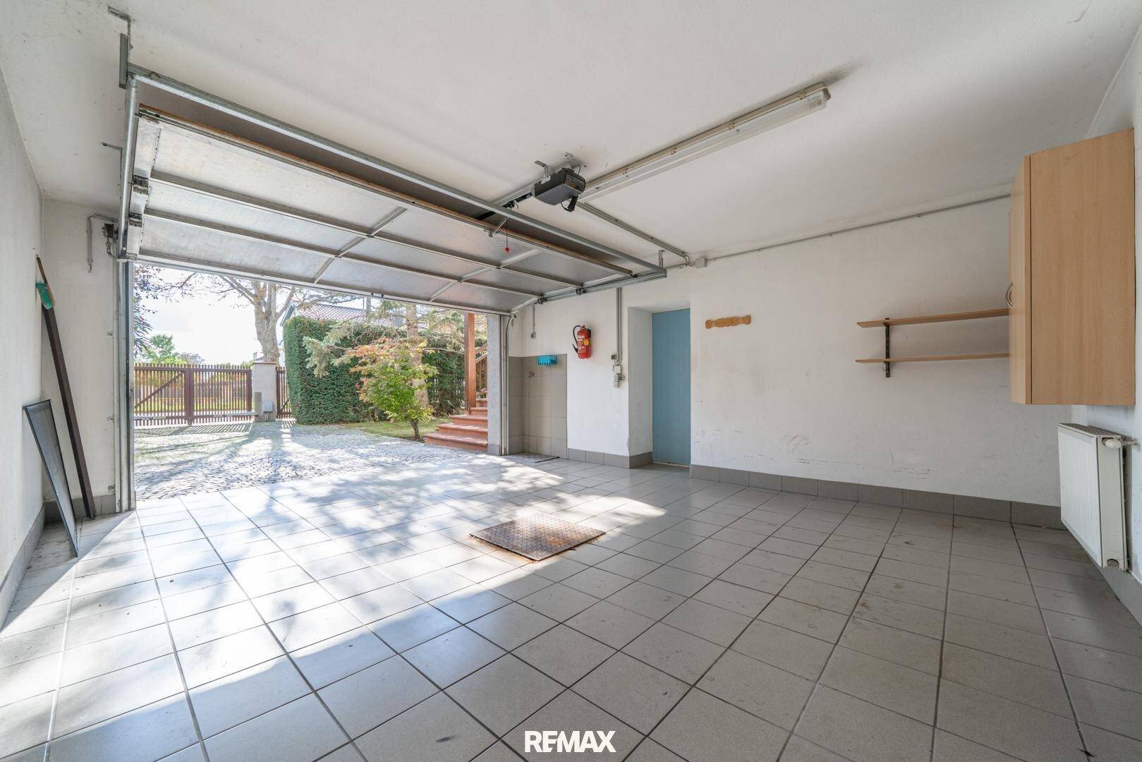 Geräumige Garage mit Fliesenboden und direktem Zugang zum Garten.