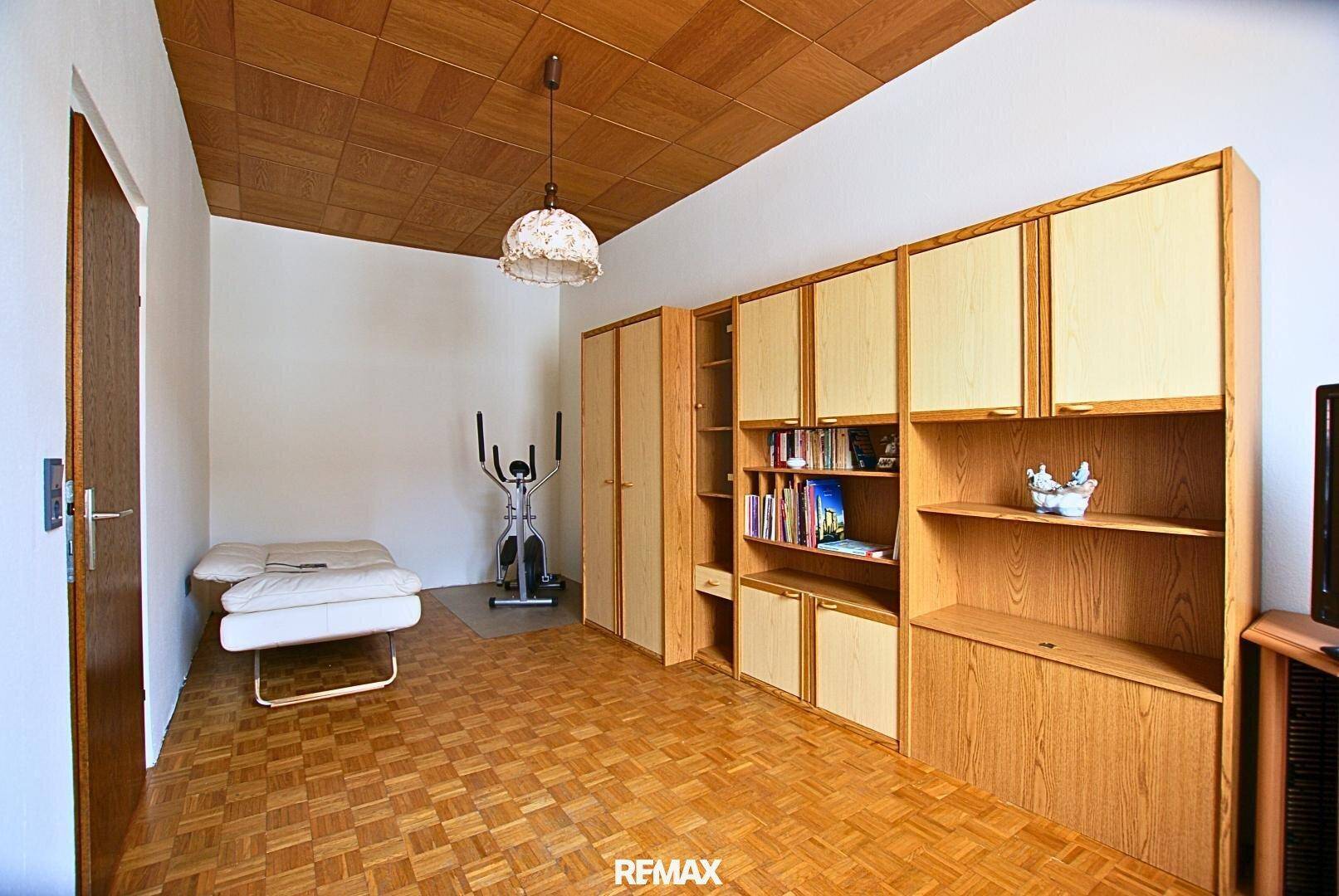 Schlafzimmer mit Schrankwand, einem Bett und einem Heimtrainer für sportliche Aktivitäten.